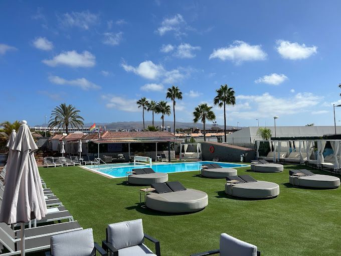 A large swimming pool surrounded by lawn chairs and umbrellas.