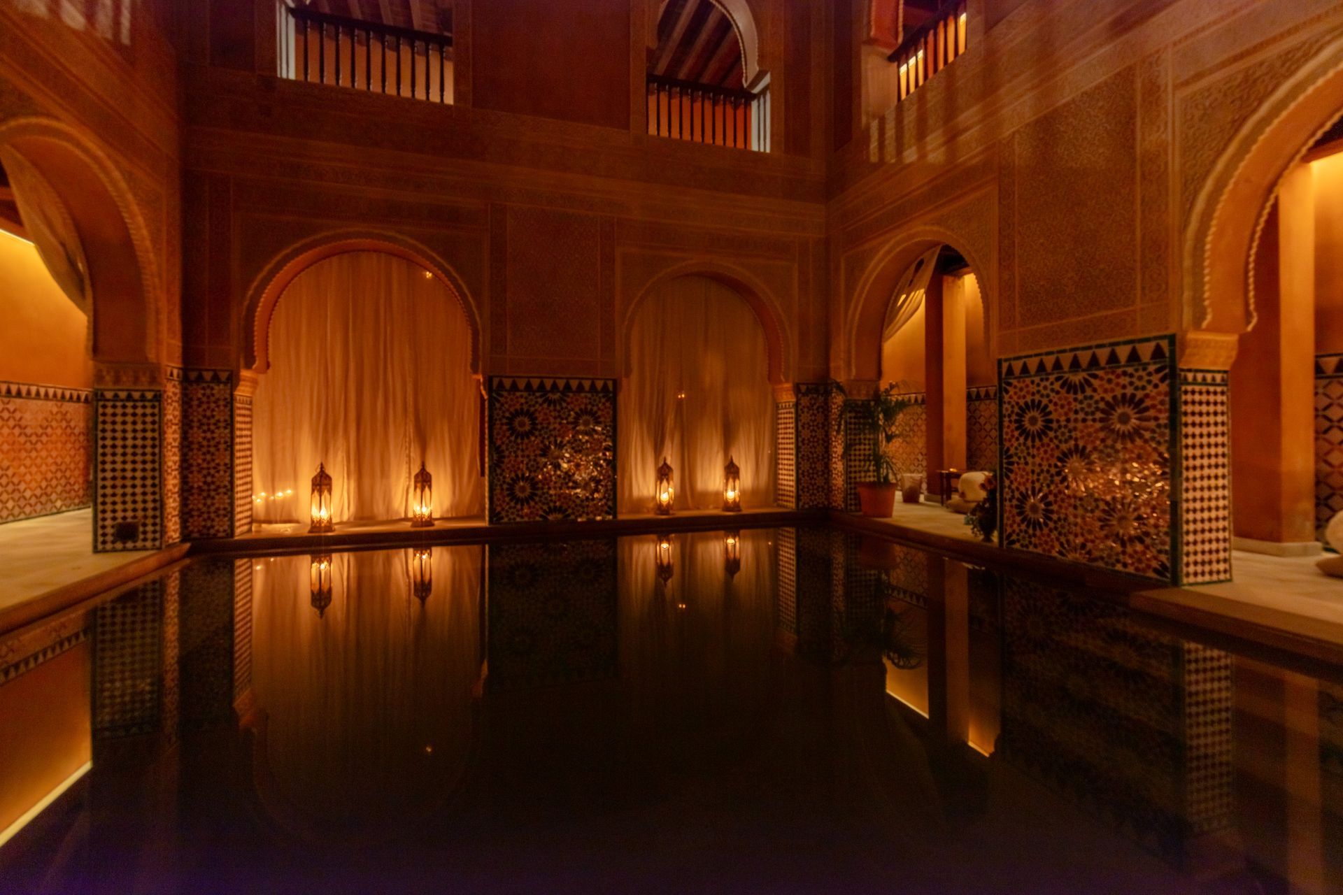 Elegant indoor pool with arched doorways, warm lighting, and decorative tile. Andalusia, Spain (thermal spas