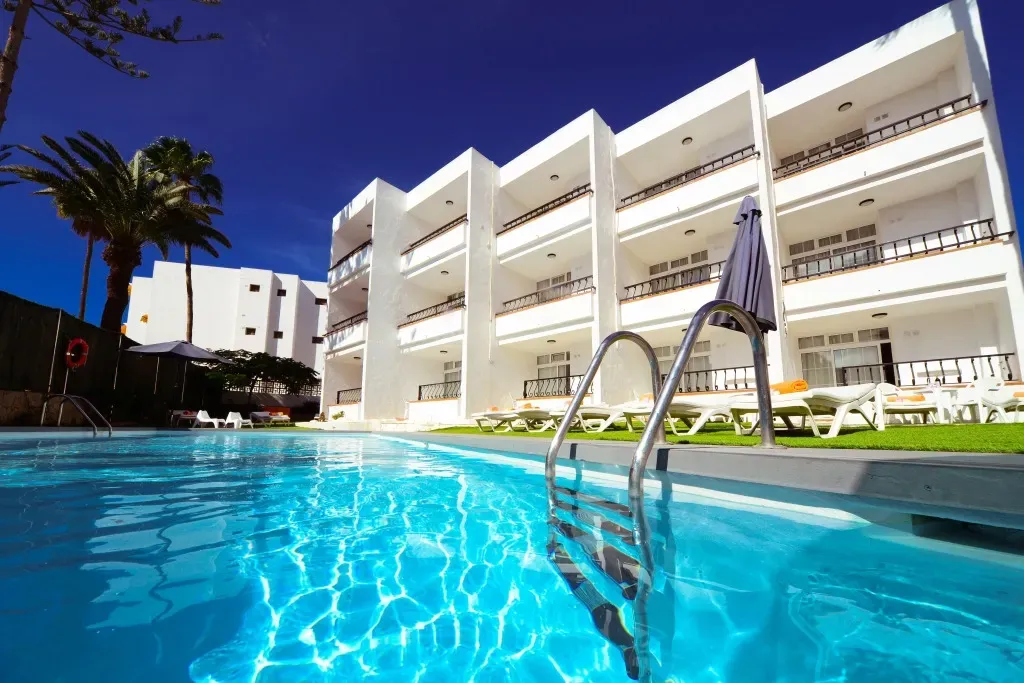 A large white building with a swimming pool in front of it.