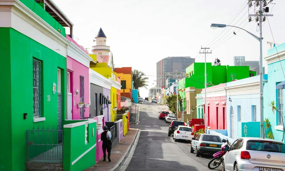 Colourful houses line a street in Bo-Kaap, Cape Town. A person walks down the road.