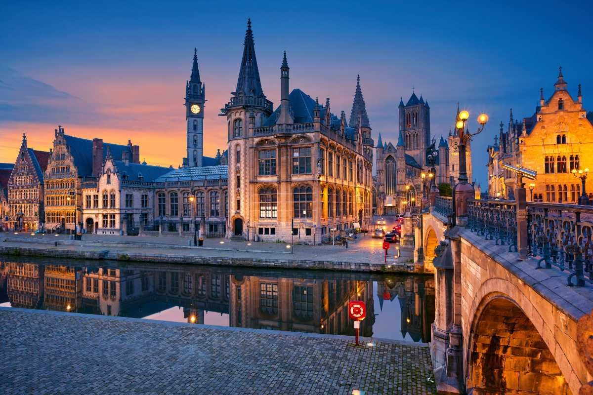 Buildings along a canal at sunset in Ghent, Belgium; reflections in water.