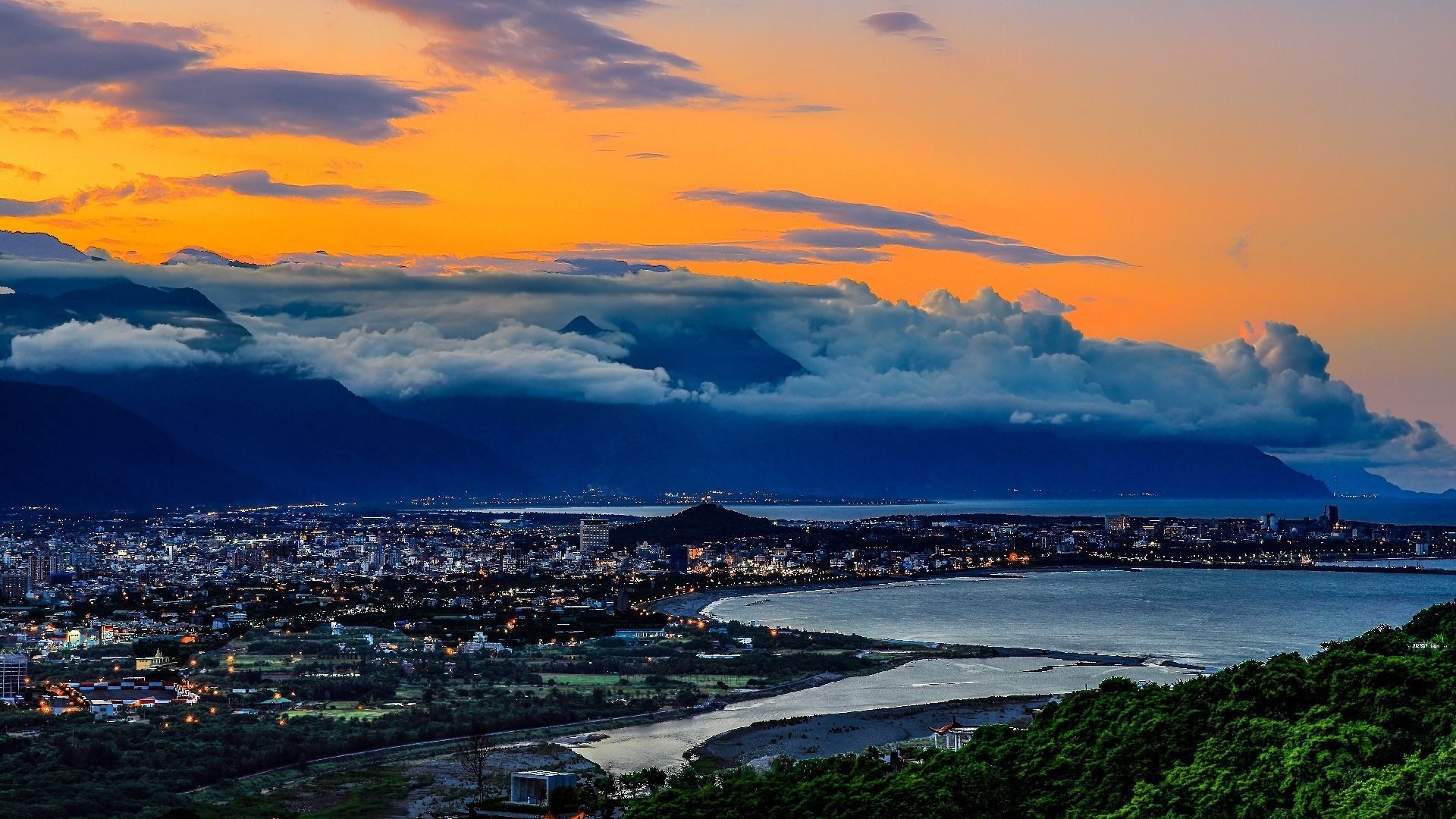 Coastal city at sunset, with mountains and clouds. Orange and blue hues. Hualien, Taiwan