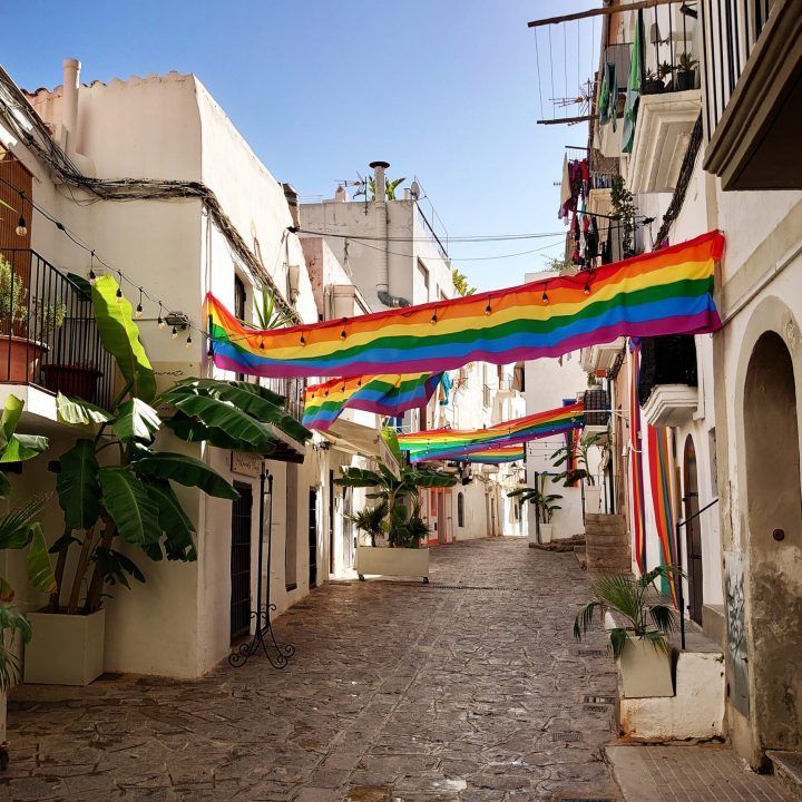 A row of buildings with rainbow flags hanging from them