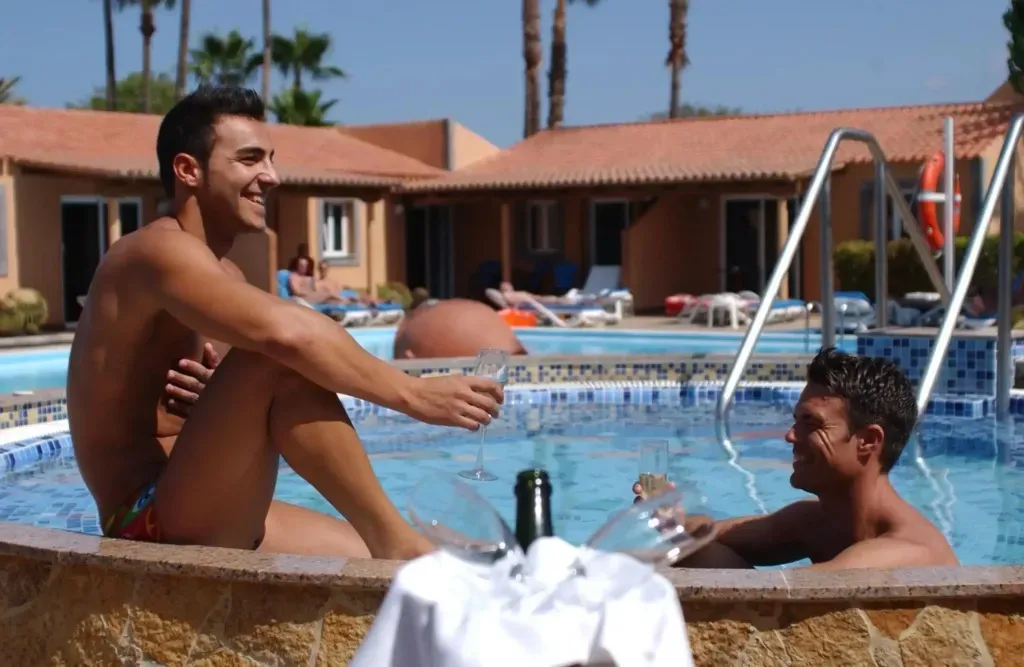 Two men are sitting on the edge of a swimming pool