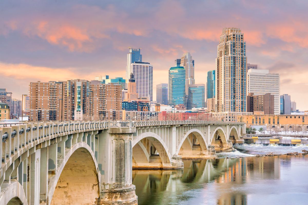 Stone arch bridge with city skyline under a colorful sunset. Minneapolis, Minnesota