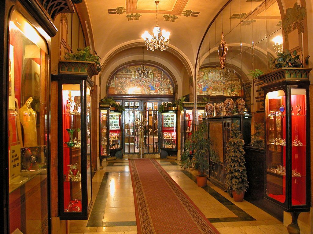 Elegant hallway with display cases, stained glass, and a red carpet.