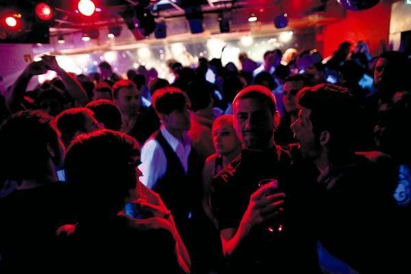 People in a crowded, dimly lit nightclub with red and blue lights; dancing and socializing. Príncipe Real