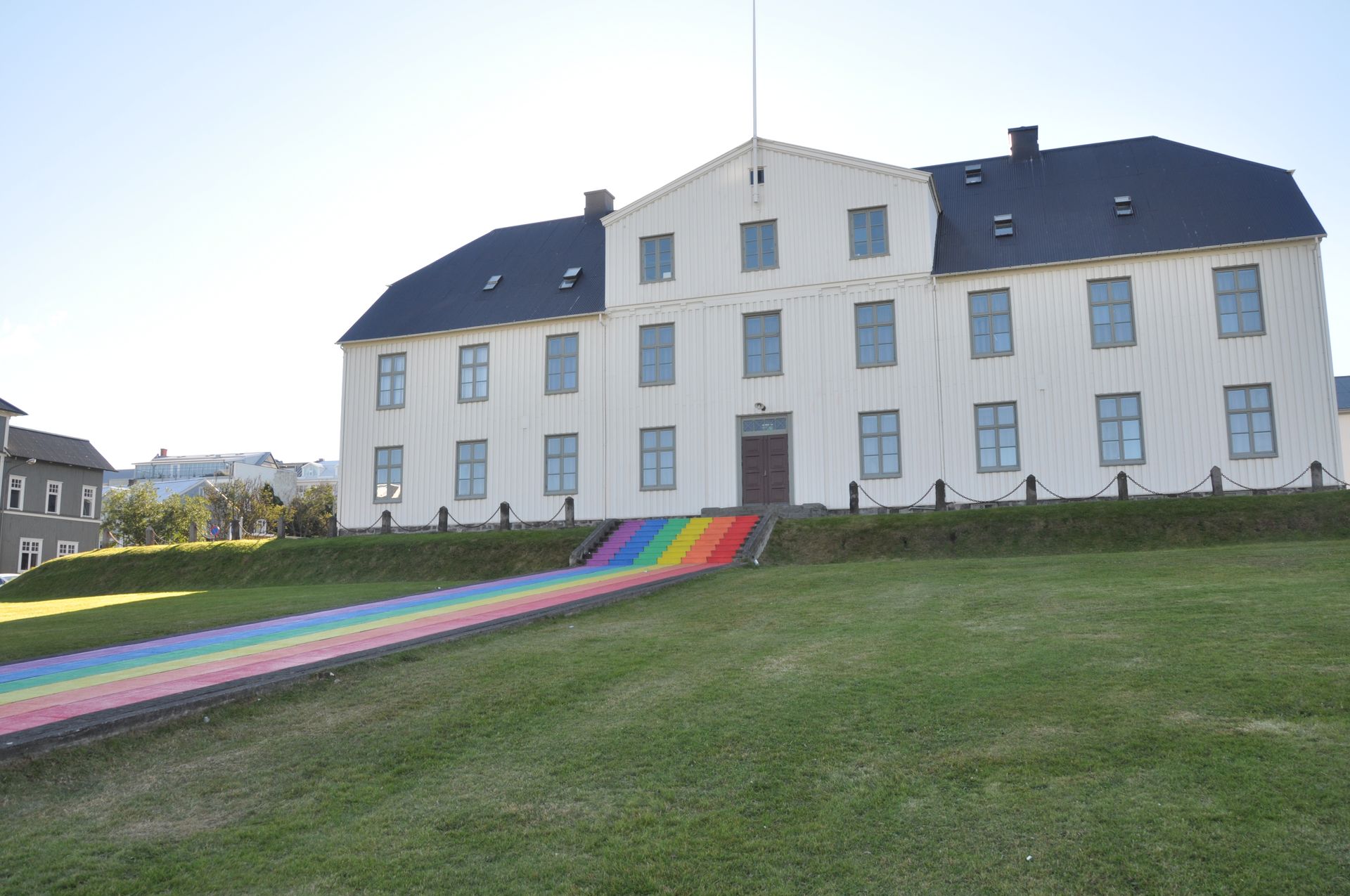 White building with rainbow steps leading up grassy hill.