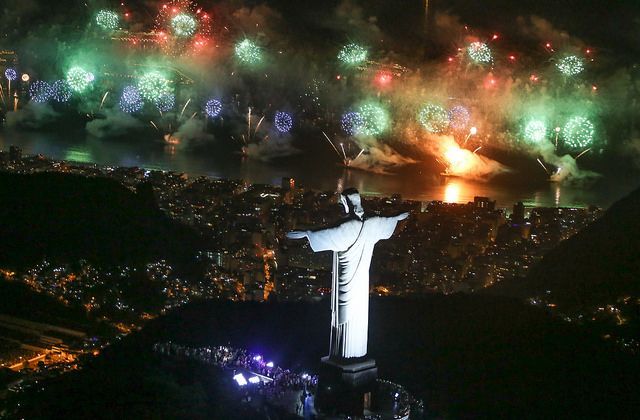 Fireworks explode over Rio de Janeiro, Brazil, with Christ the Redeemer statue in foreground.