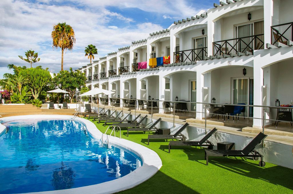 There is a large swimming pool in front of a hotel.