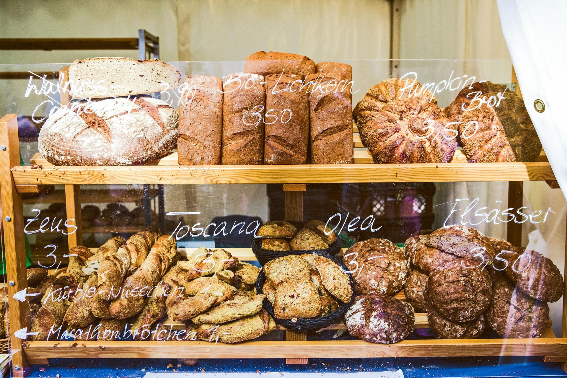 Shelves filled with various loaves of bread at a bakery, labeled with prices.