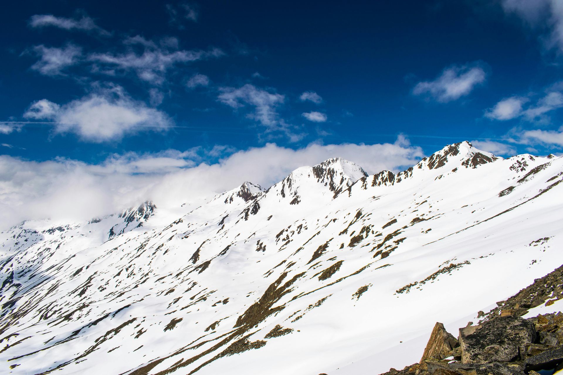 Snow-covered mountain peaks under a bright blue sky with scattered clouds.
