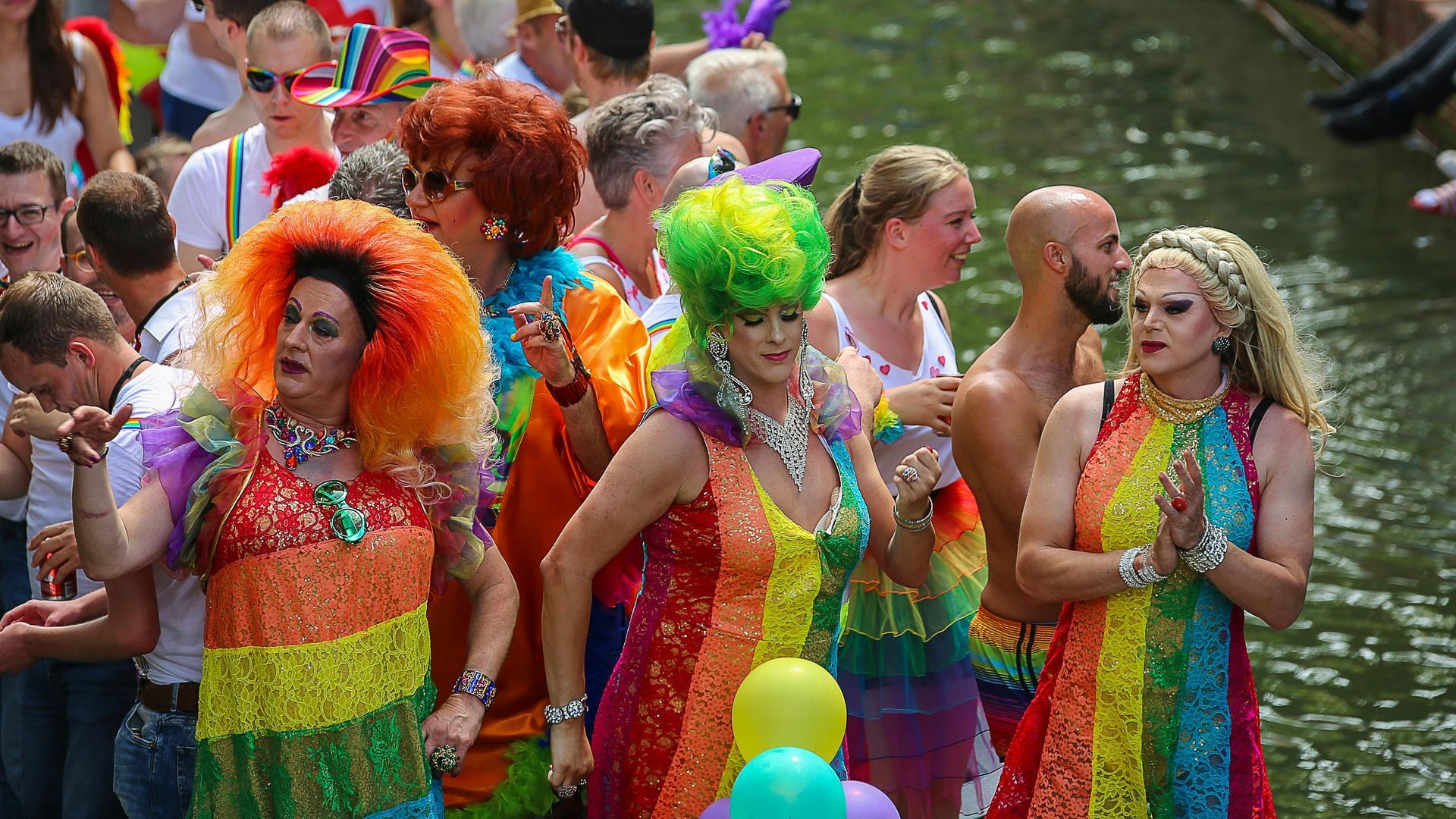 People in rainbow outfits on a boat at a Pride parade, Amsterdam.