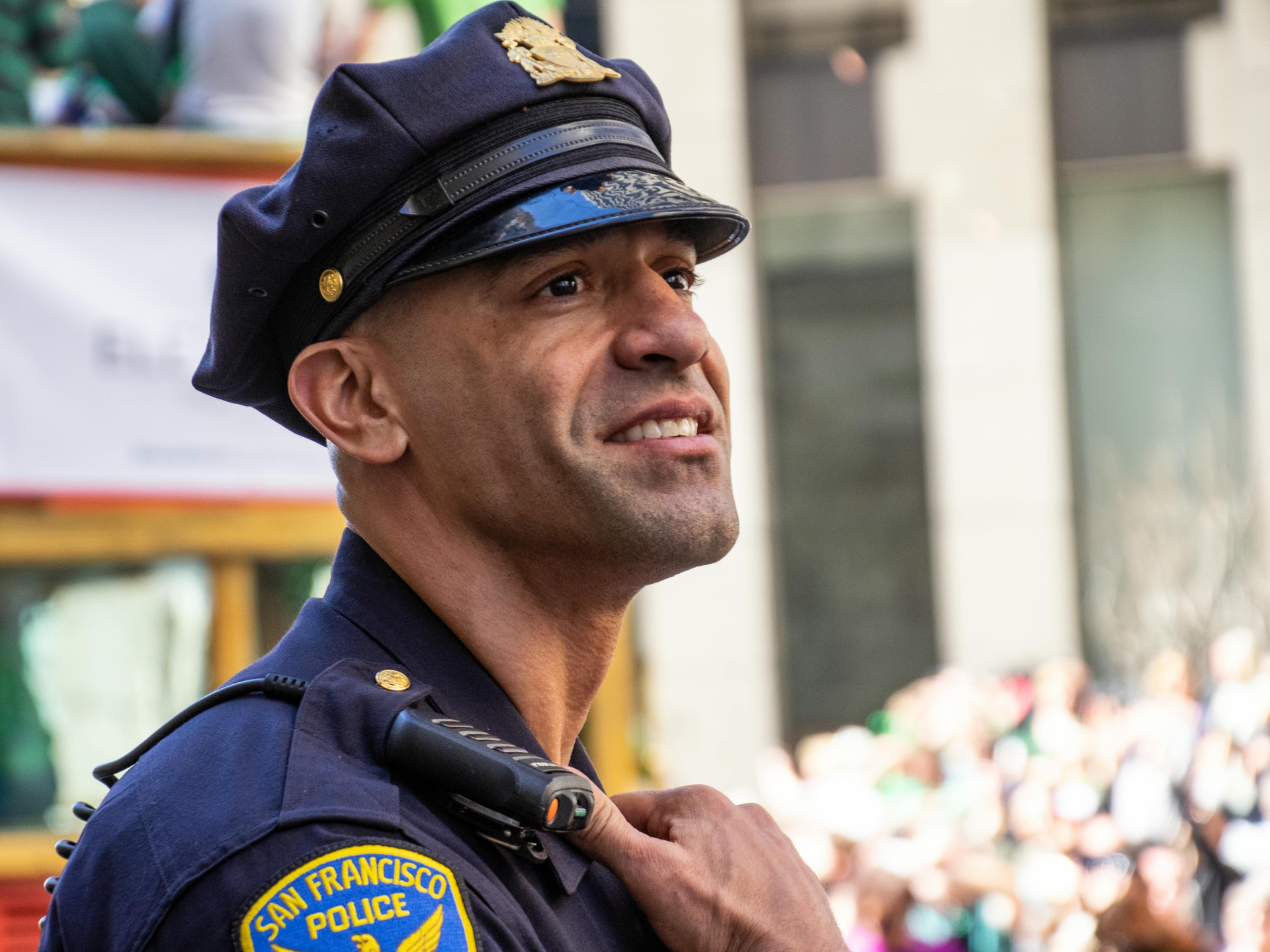 Police officer in uniform, looking upwards with a slight smile during an outdoor event.