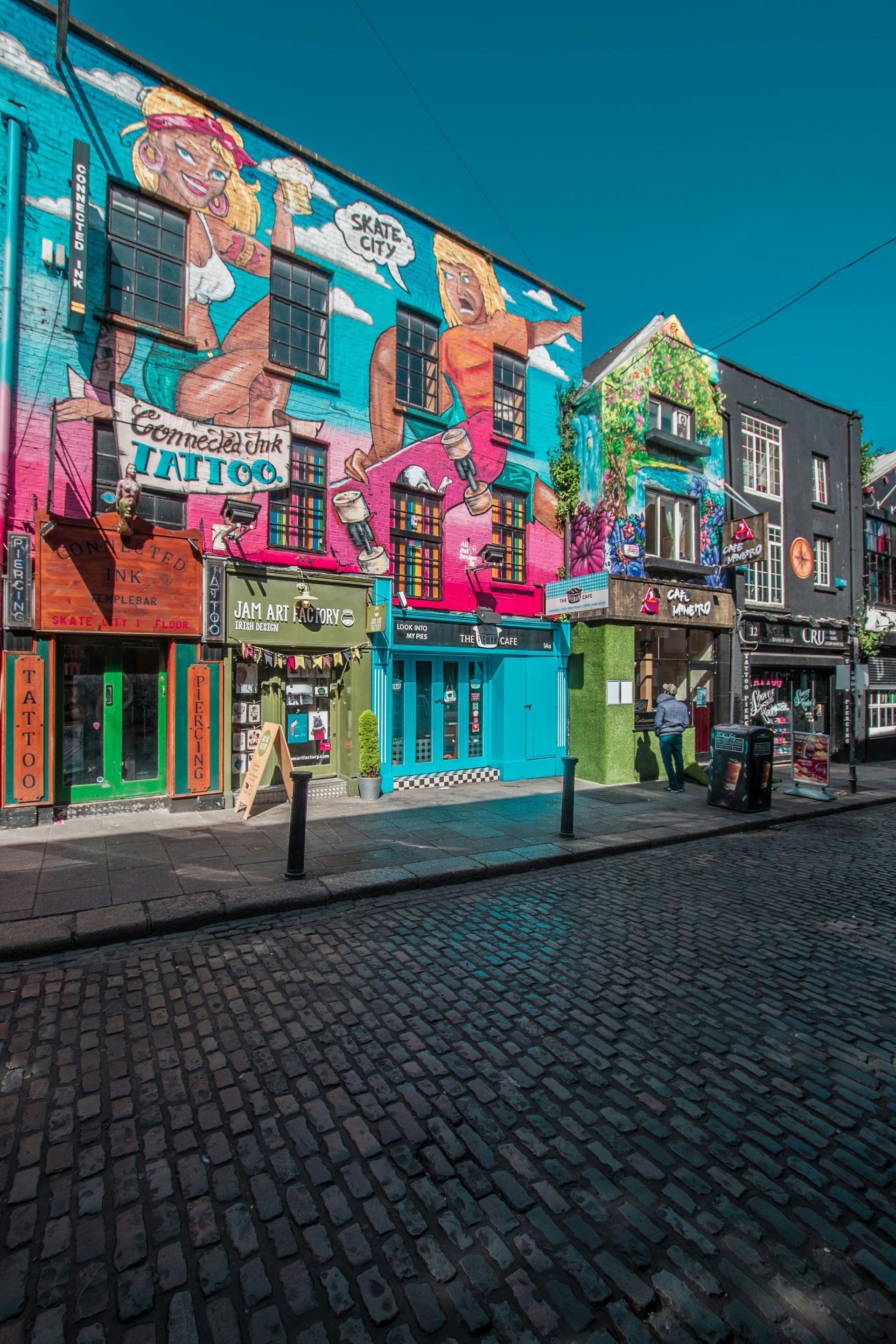 Vibrant, mural-covered building with turquoise and pink accents on a cobblestone street in Dublin, Ireland.