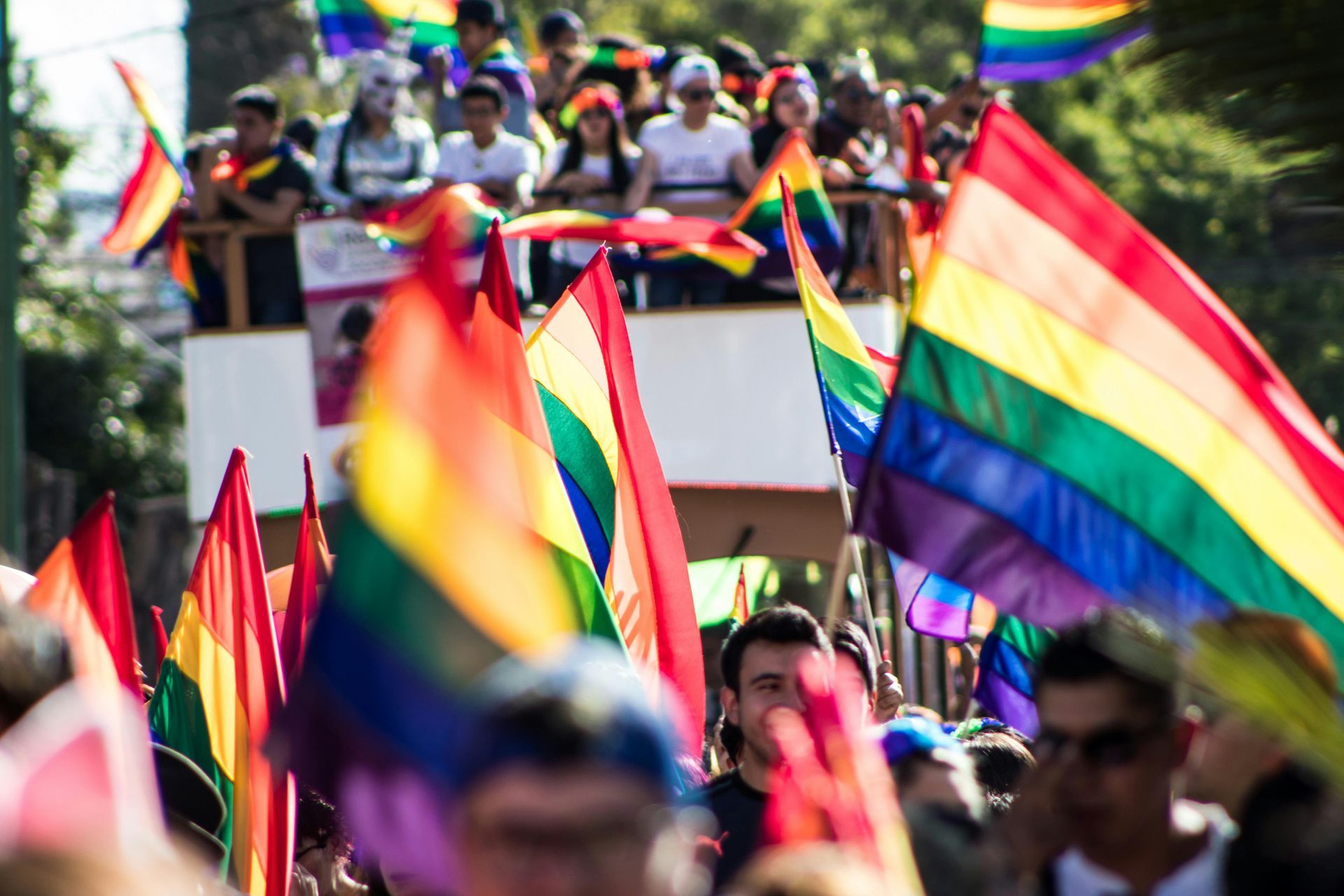 Crowd waving rainbow flags at an LGBTQ+ Pride parade.