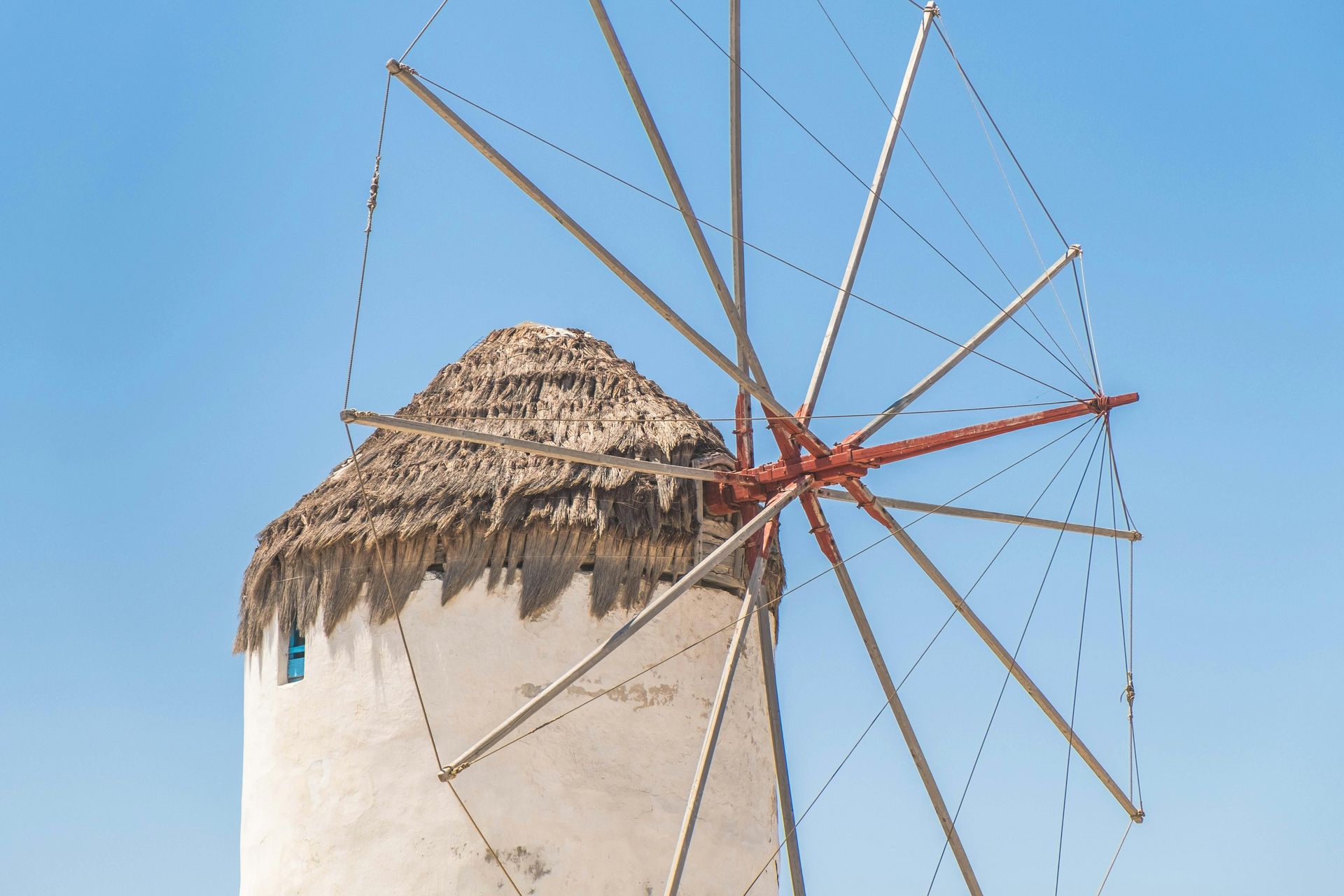 White windmill with thatched roof against a blue sky.