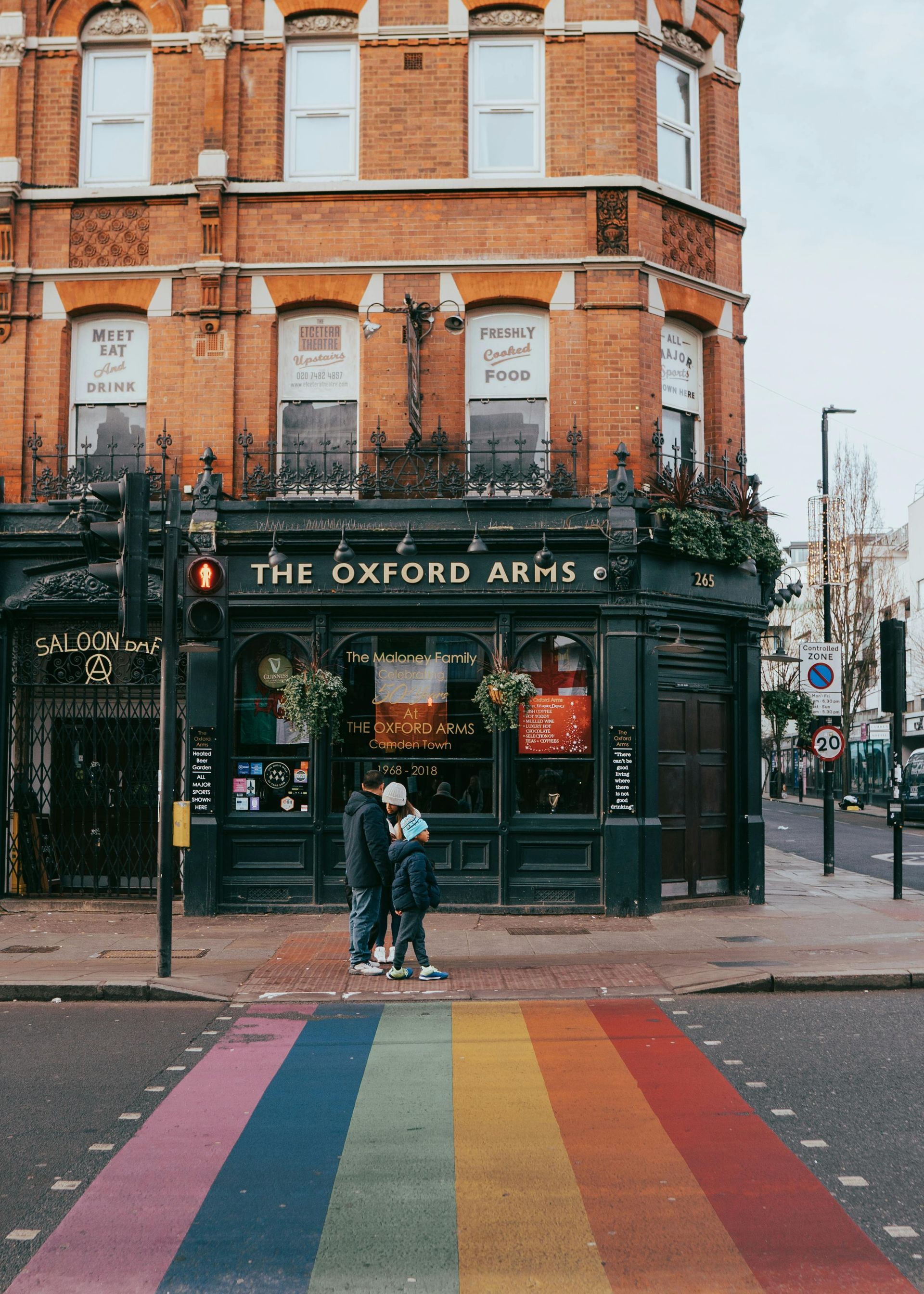 A couple stands on a rainbow crosswalk in front of