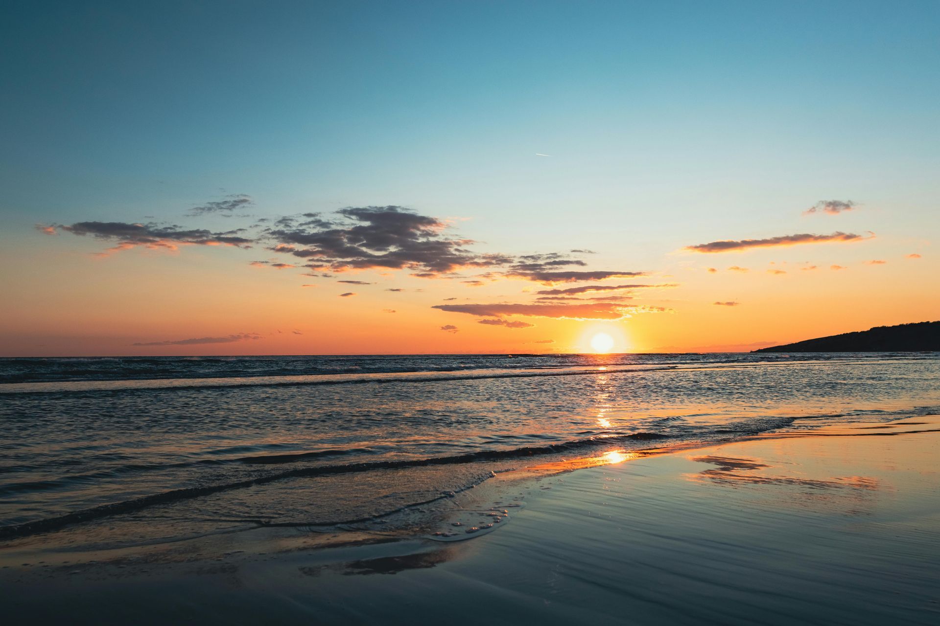 Hotel with a blue swimming pool, white building, palm trees, and sunny sky.