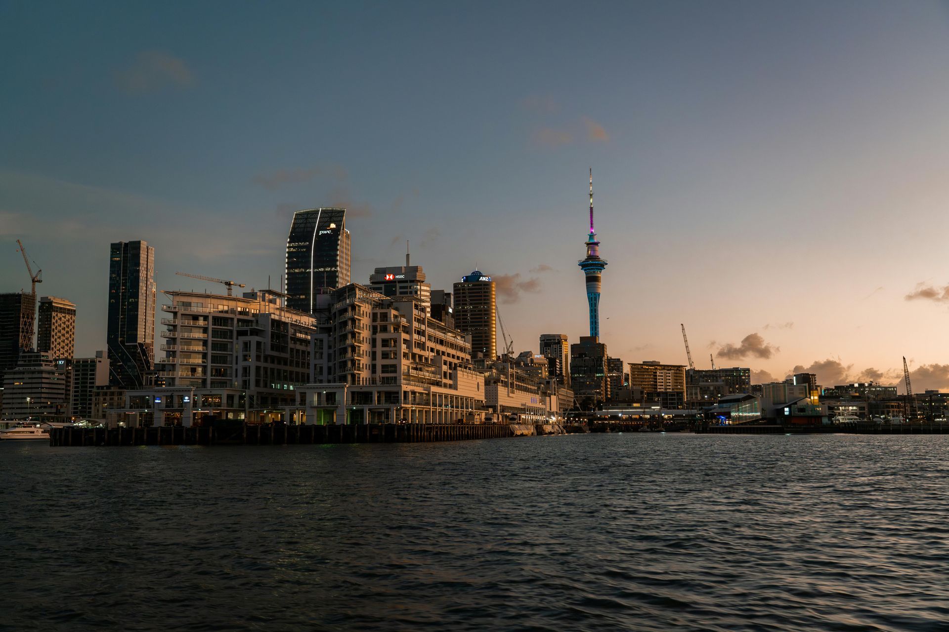 Auckland skyline at dusk, featuring the Sky Tower and harbor.