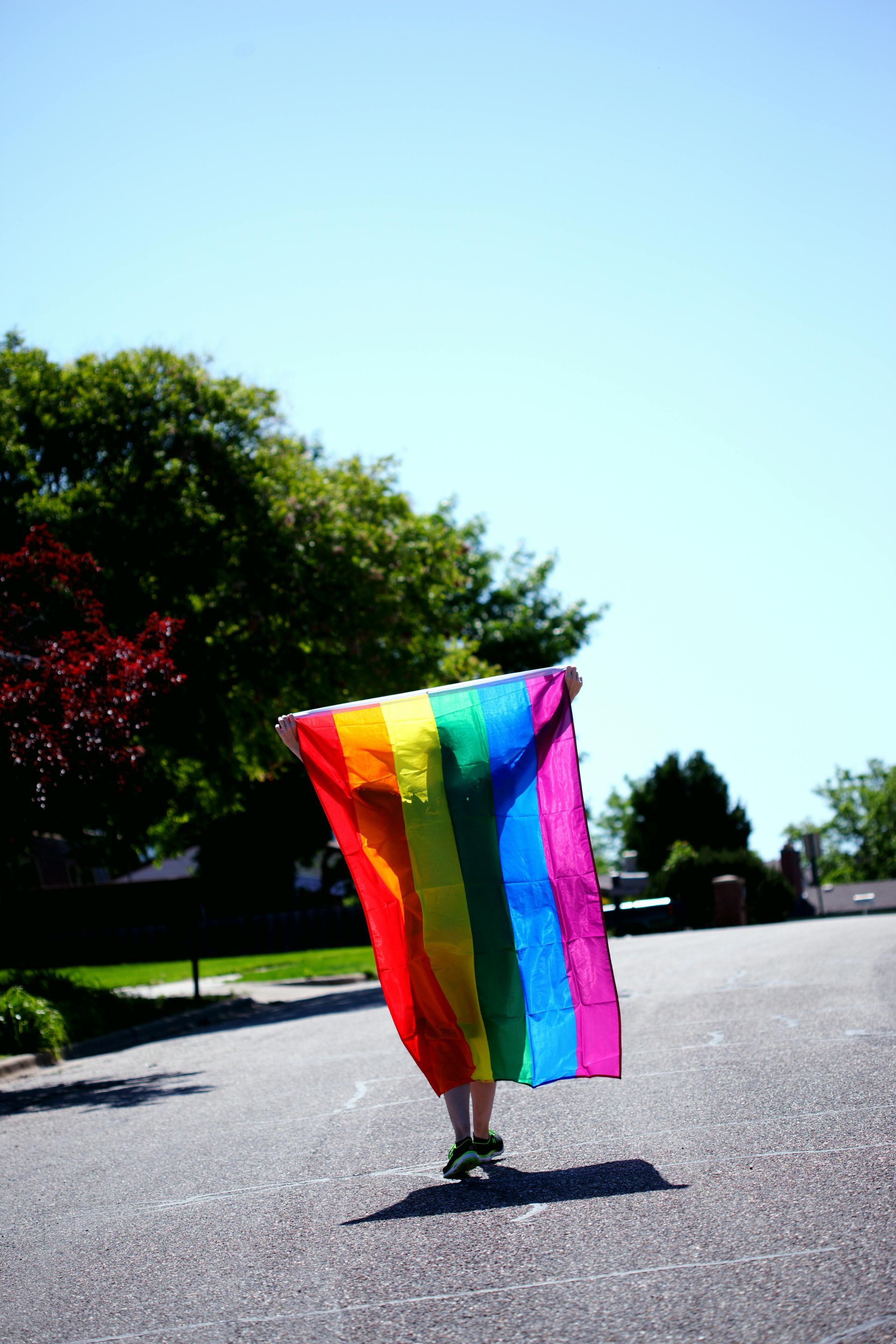 Person holding a rainbow flag outdoors on a sunny day. Cape Town Pride: Pride at the Tip of Africa