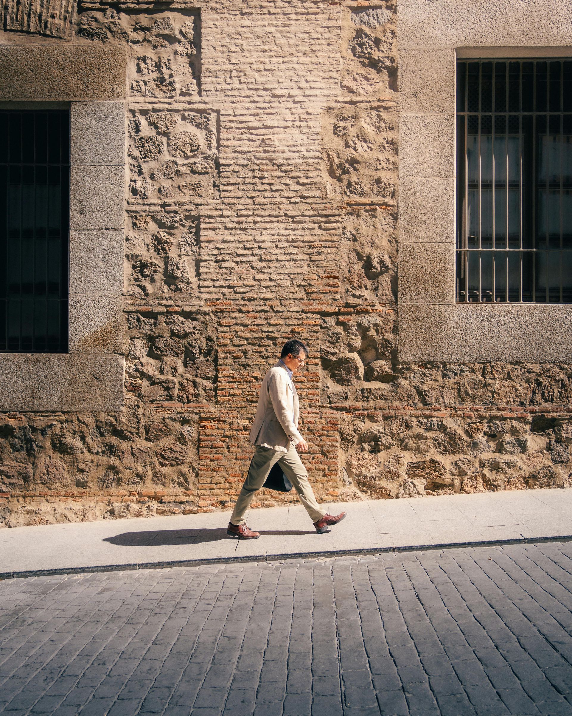 Person with arms outstretched atop green hills, mountain in background, cloudy sky.