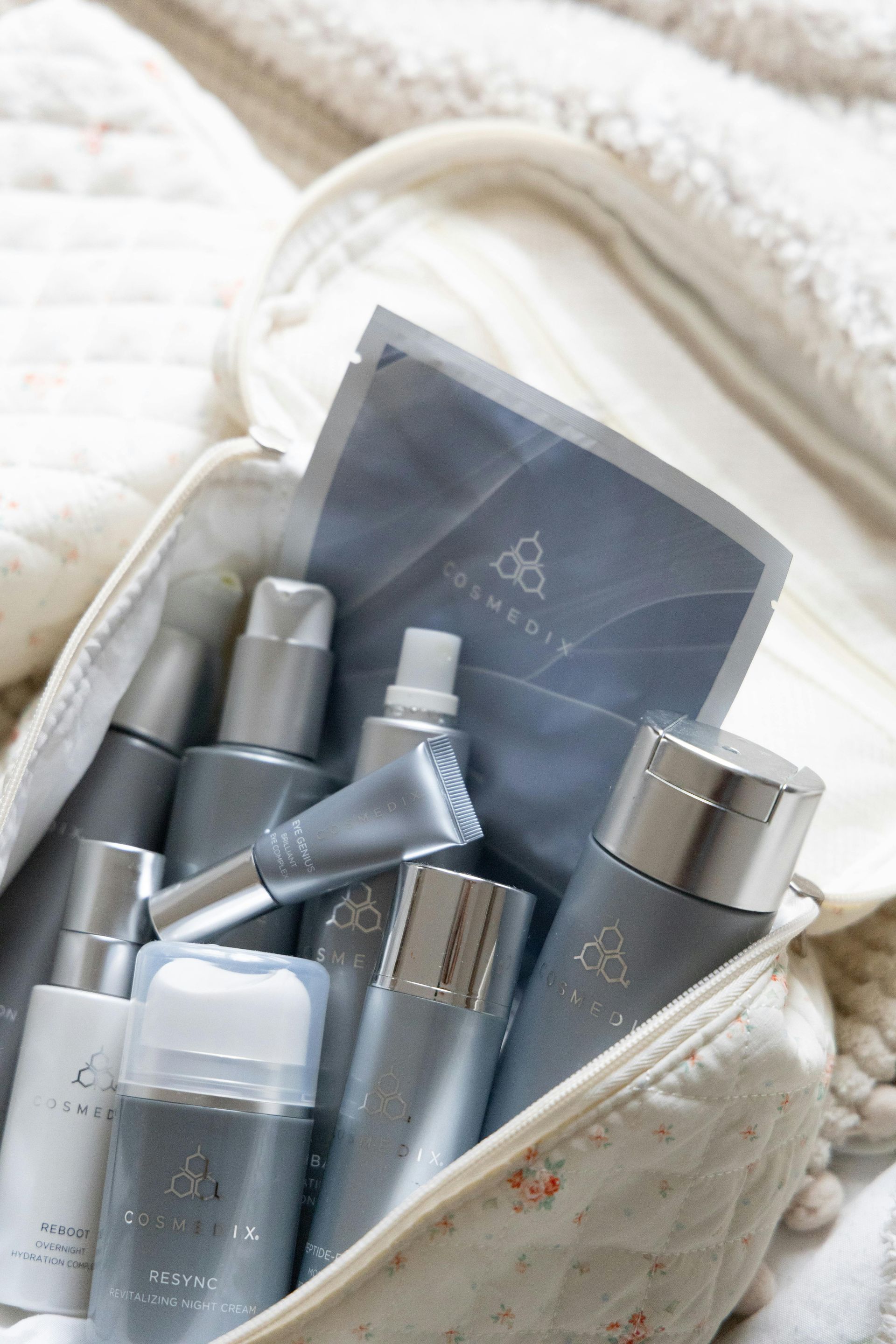 Cosmetic products in a white bag, gray and silver bottles.