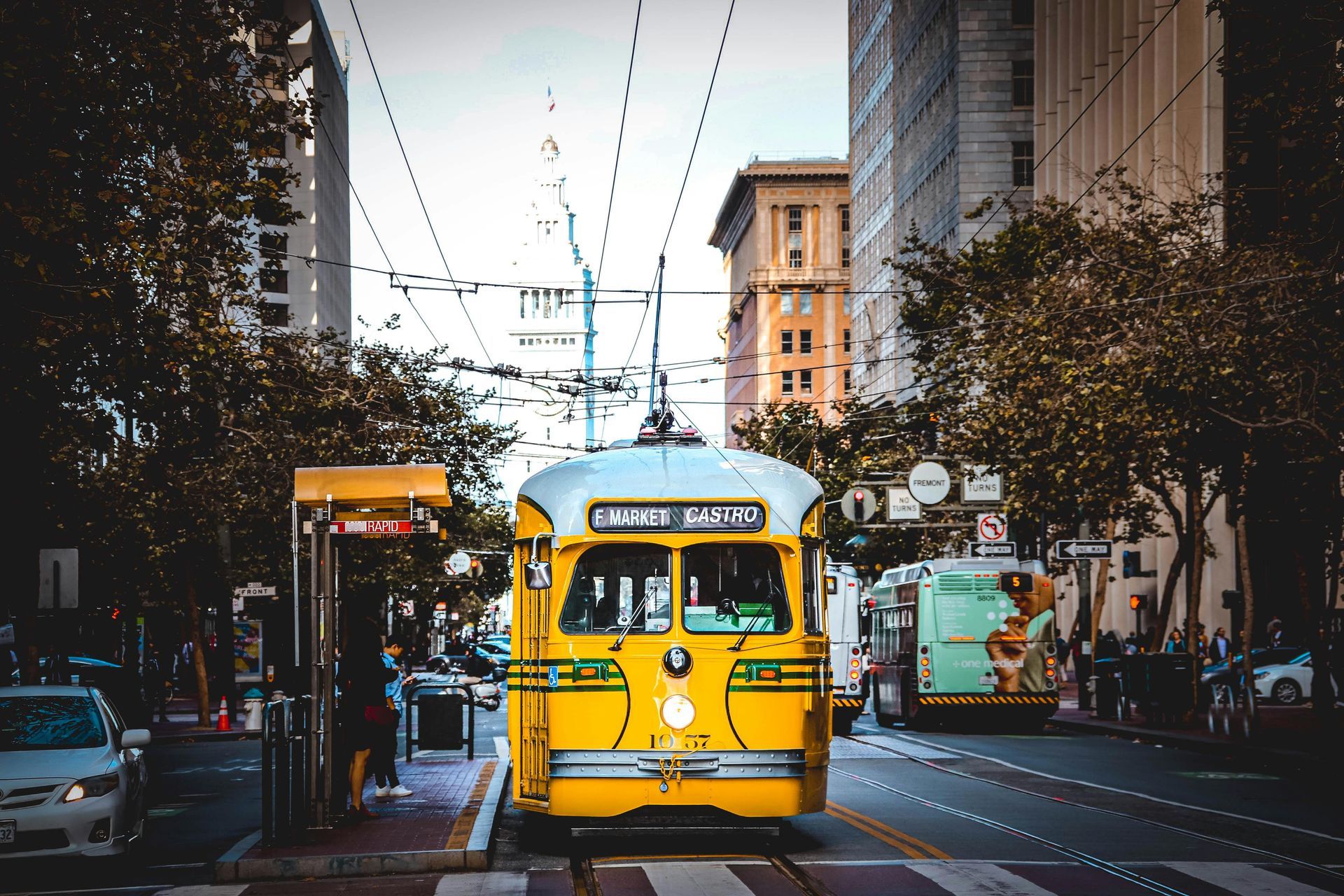 Yellow streetcar on city street, brown buildings in background. Castro District