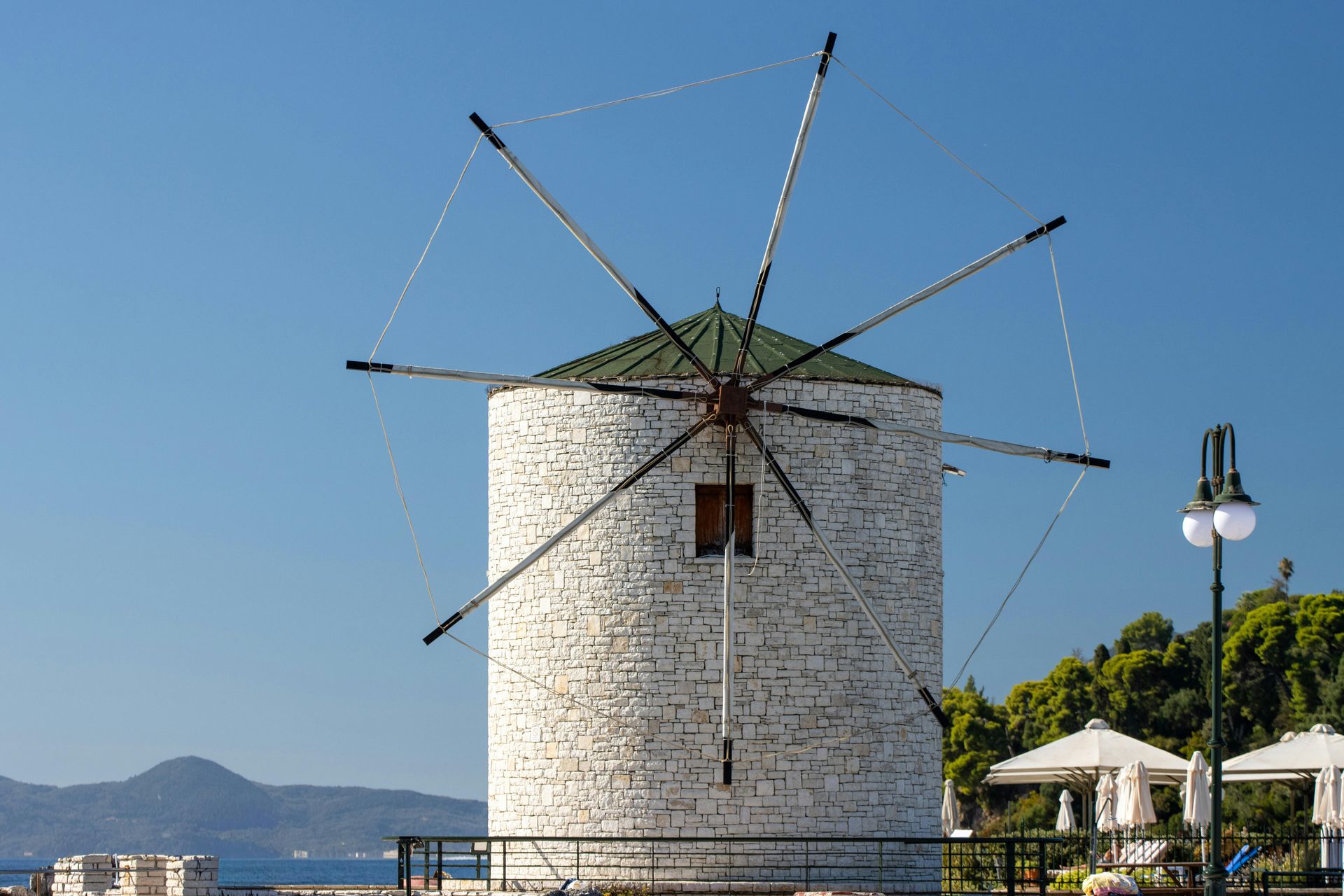 White stone windmill with blades against a blue sky. Corfu