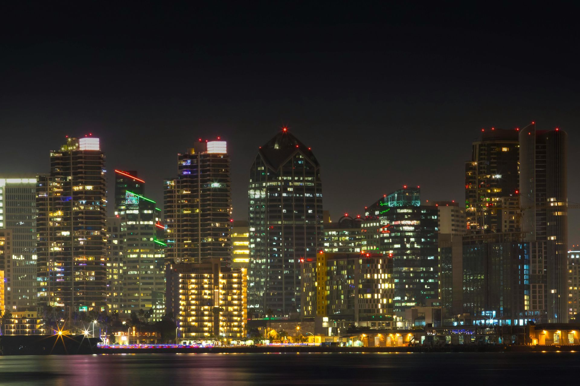 City skyline at night with lights reflecting on water.