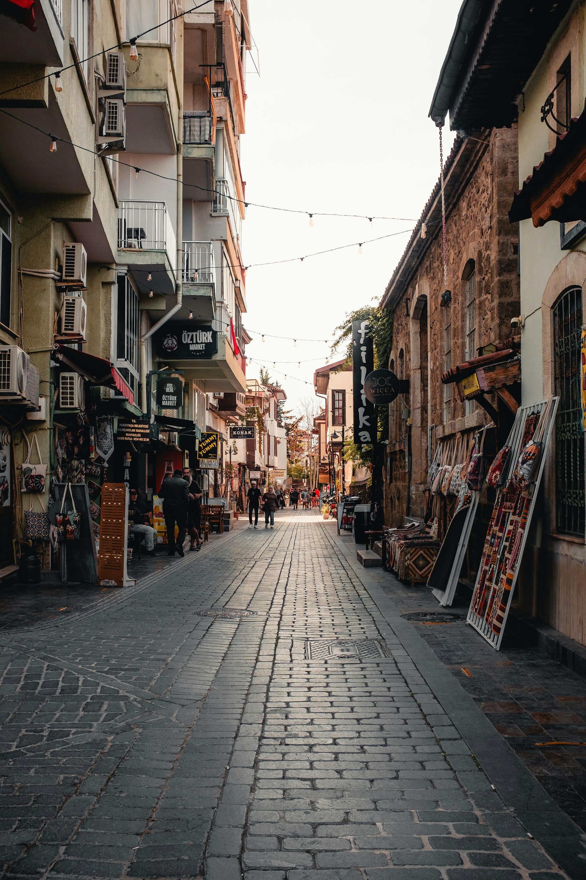 A low-angle view of a historic cobblestone street lined with tall brick buildings and faded yellow double road markings.