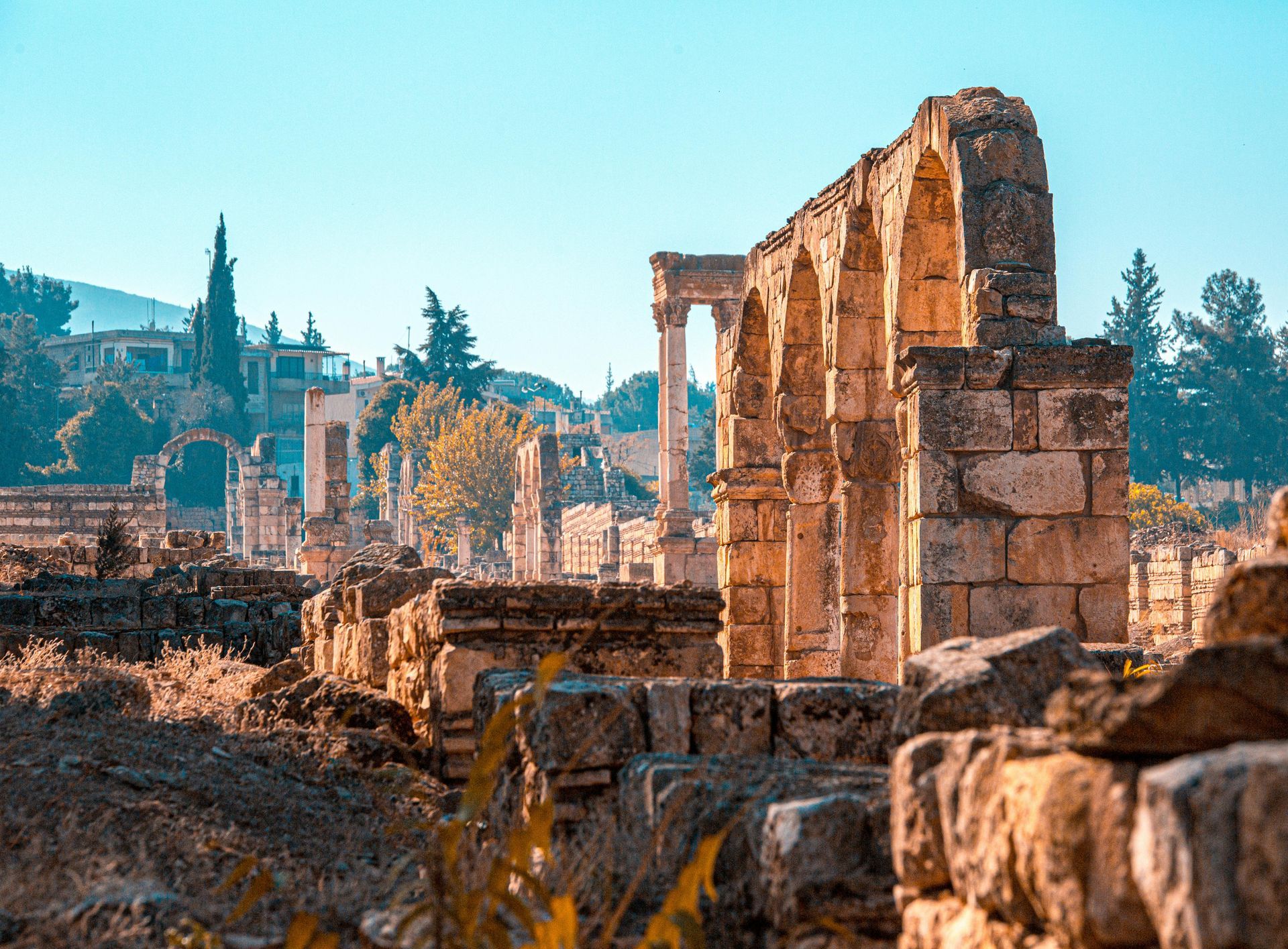 Ruins of ancient stone structures in a sunny, outdoor setting. Arches, pillars, and remnants of walls. lebanon