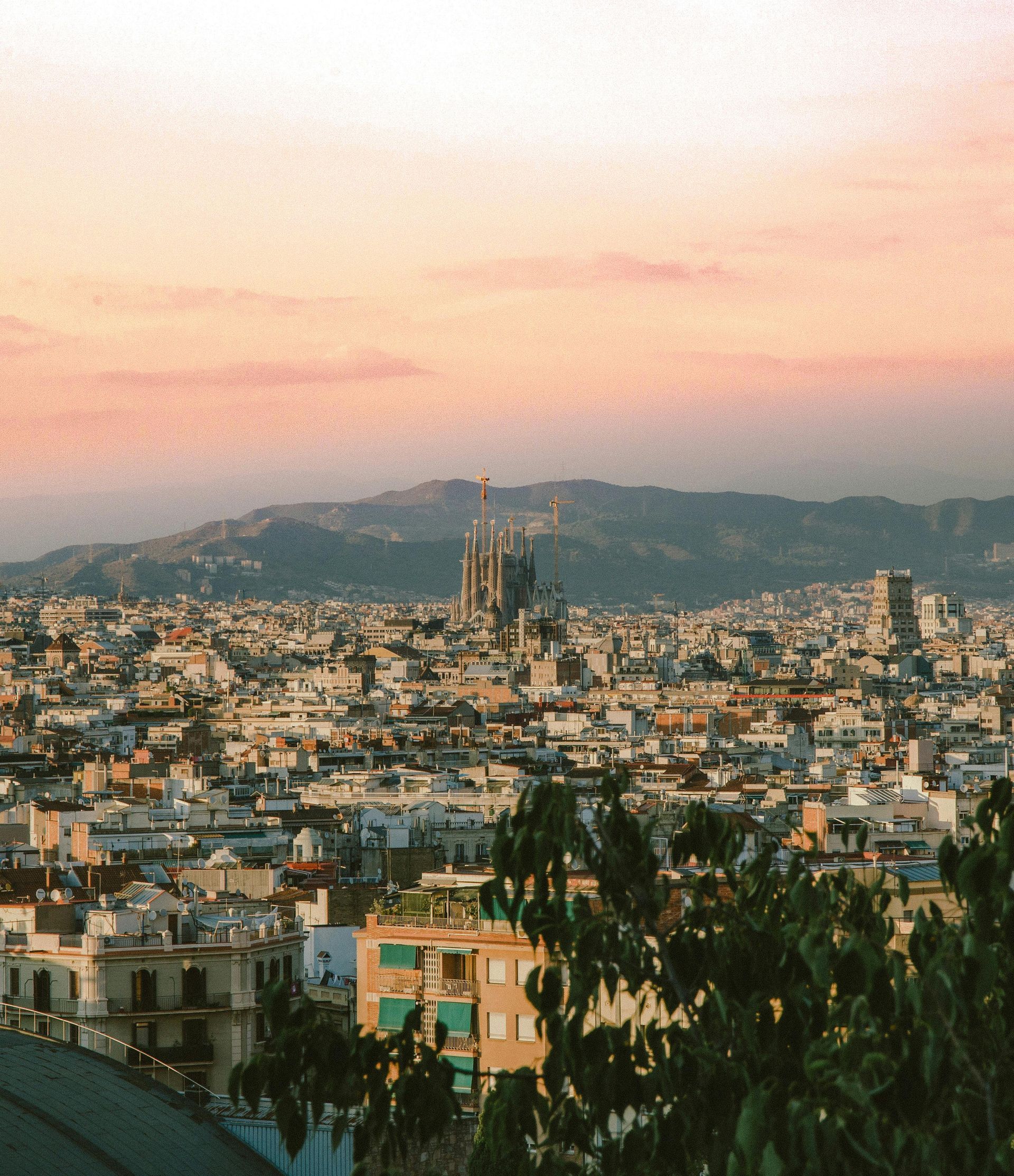 City skyline at sunset, with a prominent cathedral in the distance.