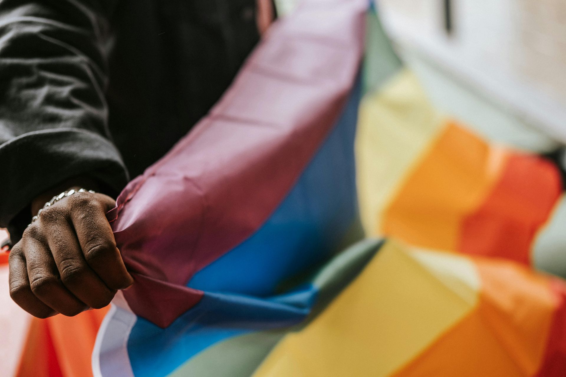 Person holding a rainbow pride flag, partially visible.