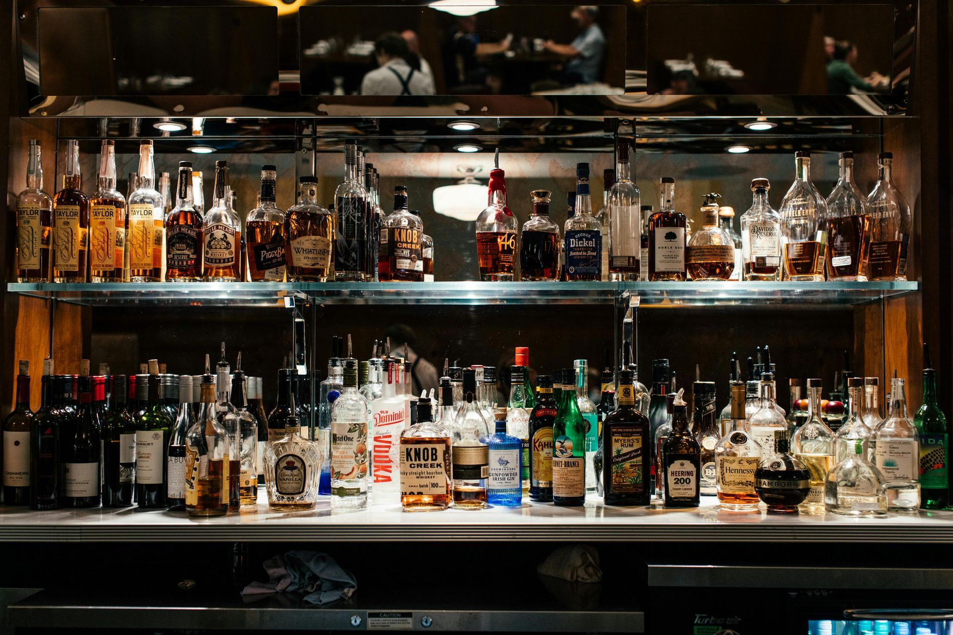 Bar with numerous liquor bottles on display, bottles in different shapes, colors, and labels, with soft lighting.