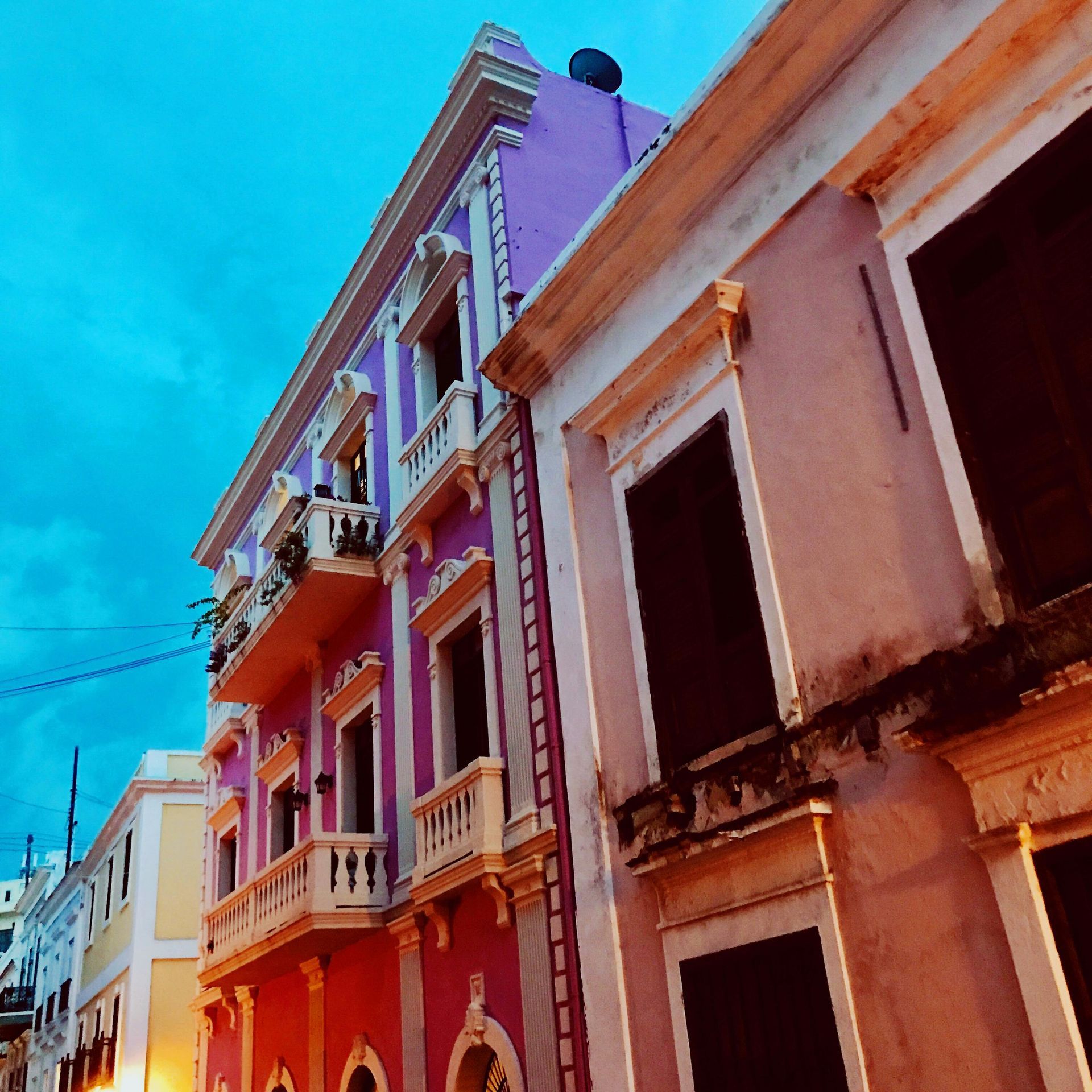 Colorful buildings in Old San Juan, Puerto Rico. Pink, purple, and yellow facades under a blue sky. Puerto Rico