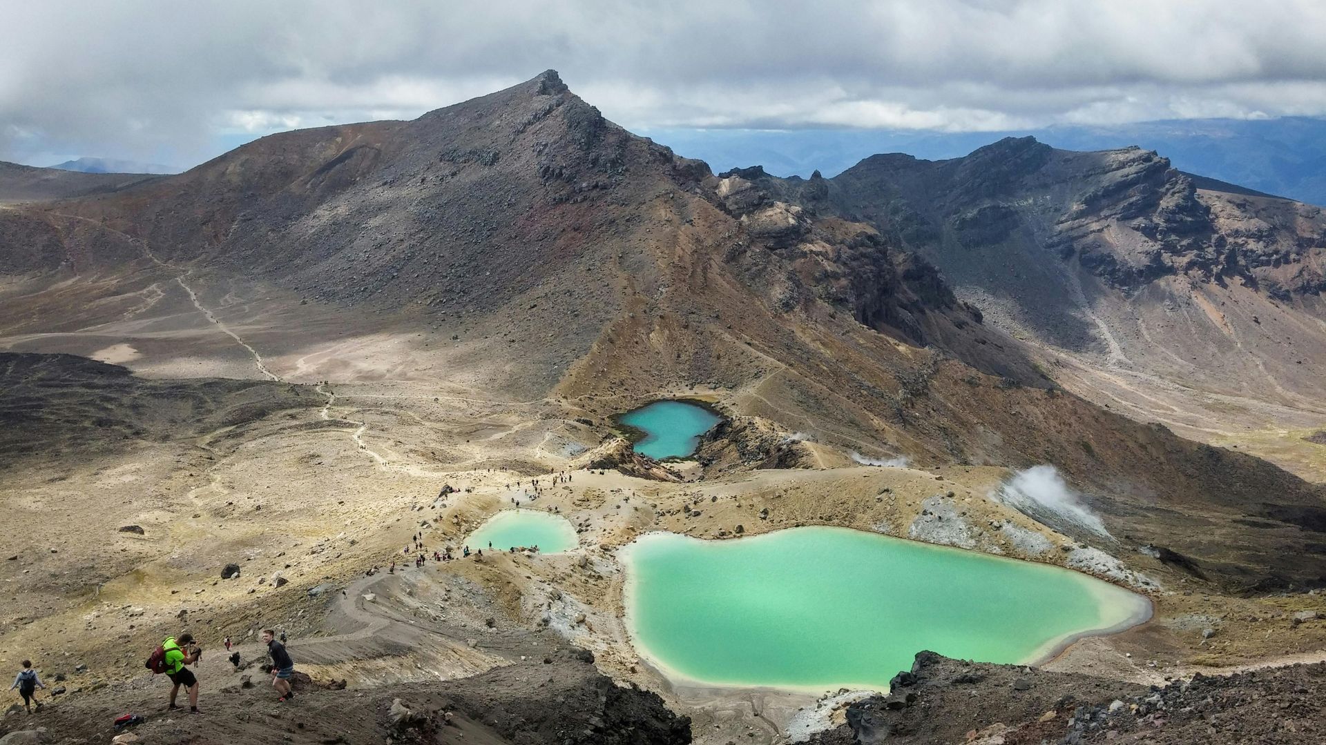 Mountain landscape with turquoise lakes; hikers on a trail.Tongariro Alpine Crossing,