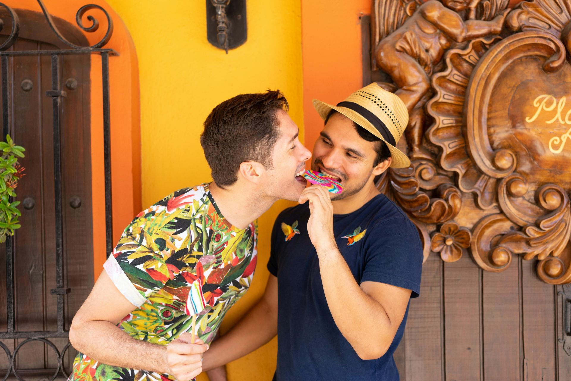 Man with beard and woman with rainbow boa pose by an ATM.