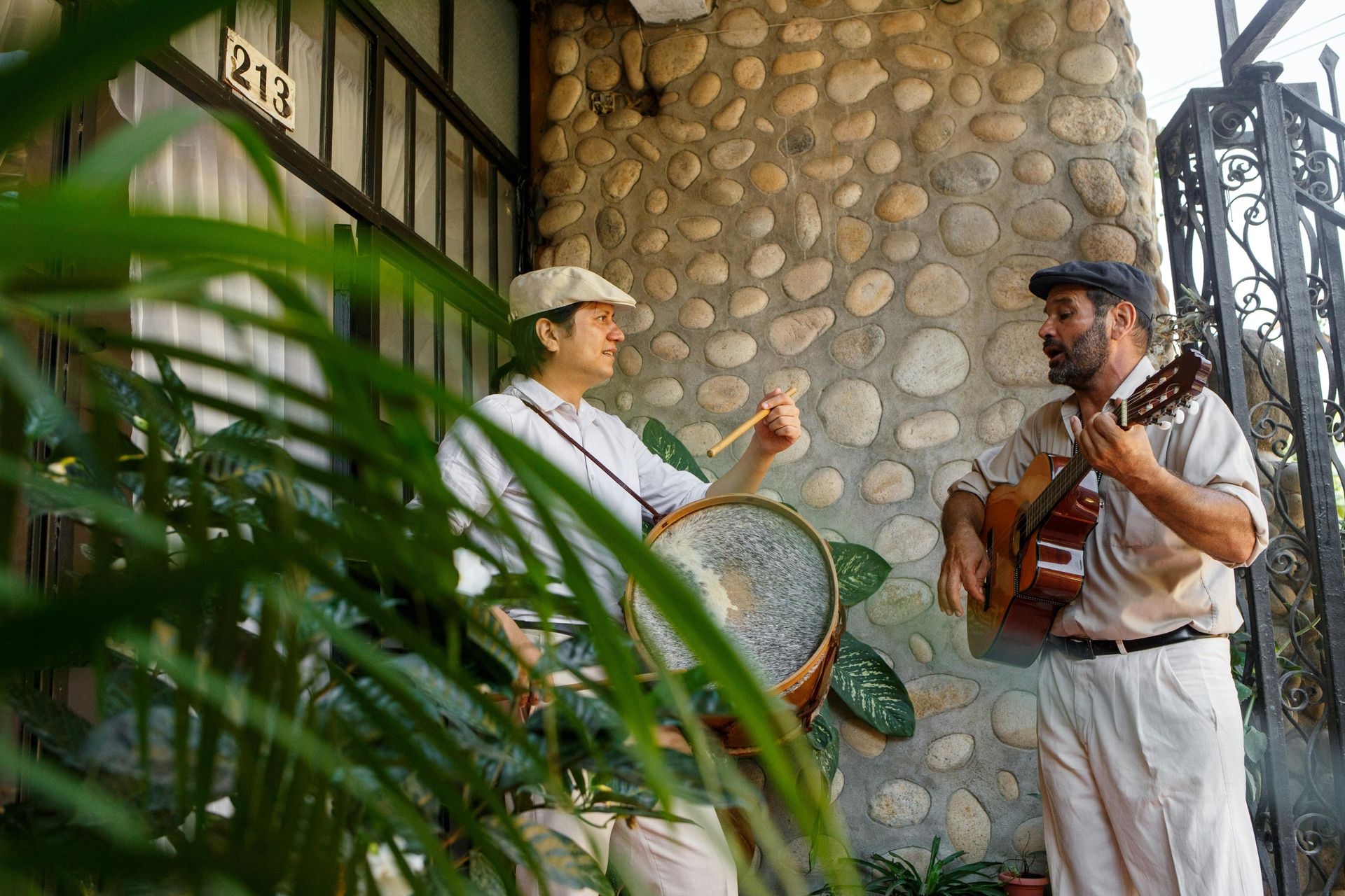 Two men playing music outside a building; one drums, the other plays guitar. Buenos Aires