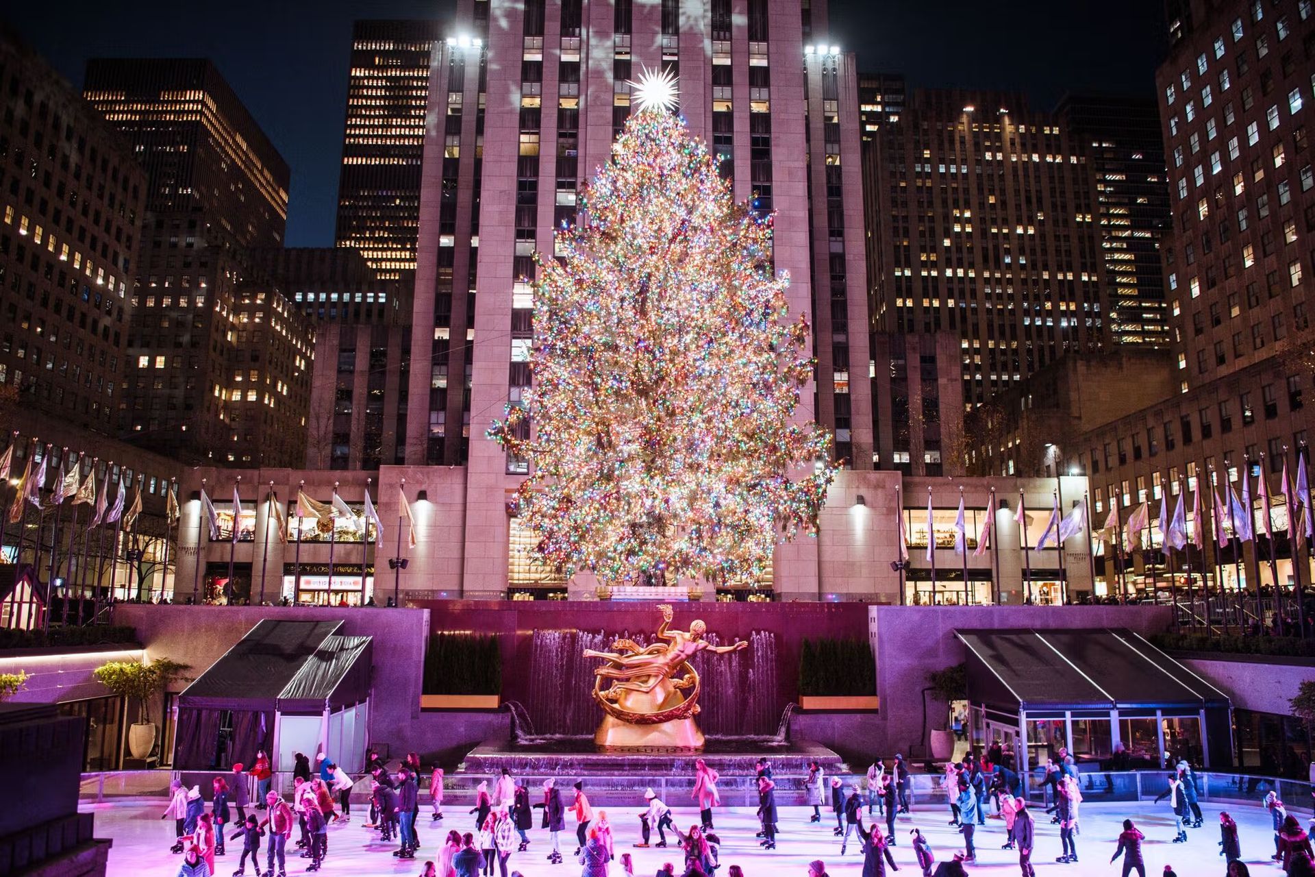 Rockefeller Center Christmas tree with ice skaters, New York City at night.