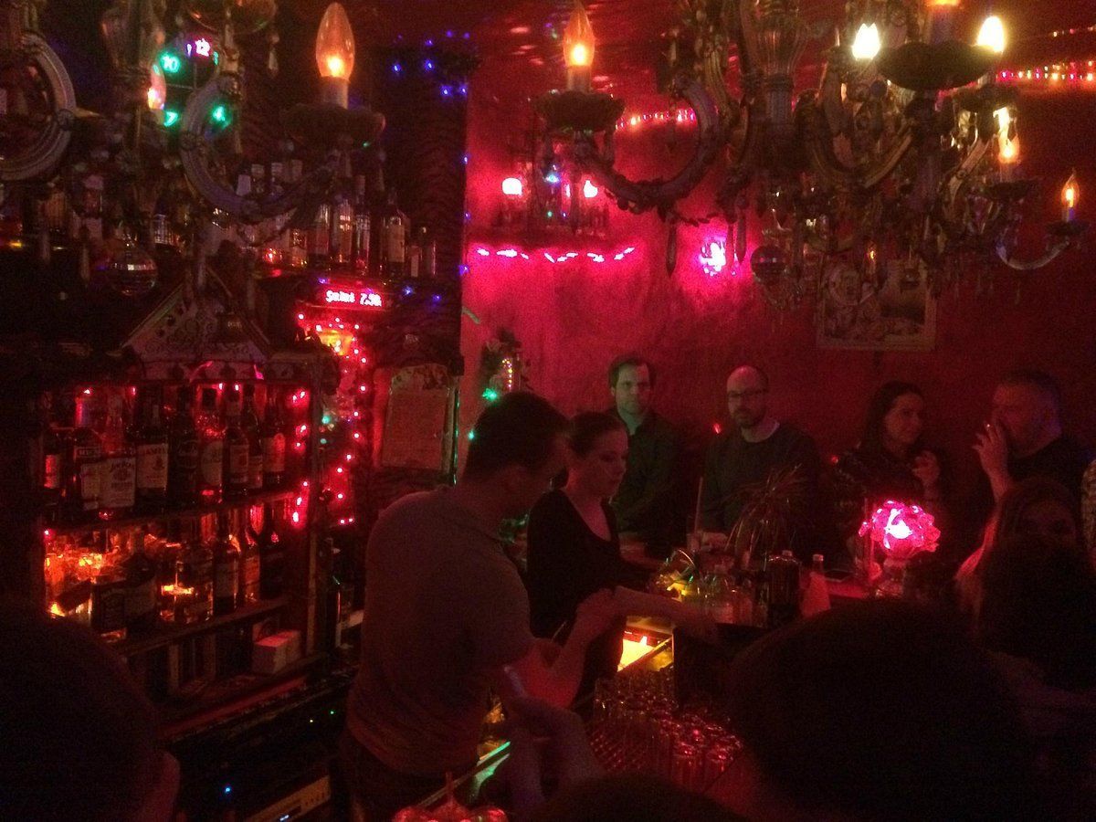 Dimly lit bar with people, bottles, and decorative lights. Bartender at work. Roses Bar Berlin
