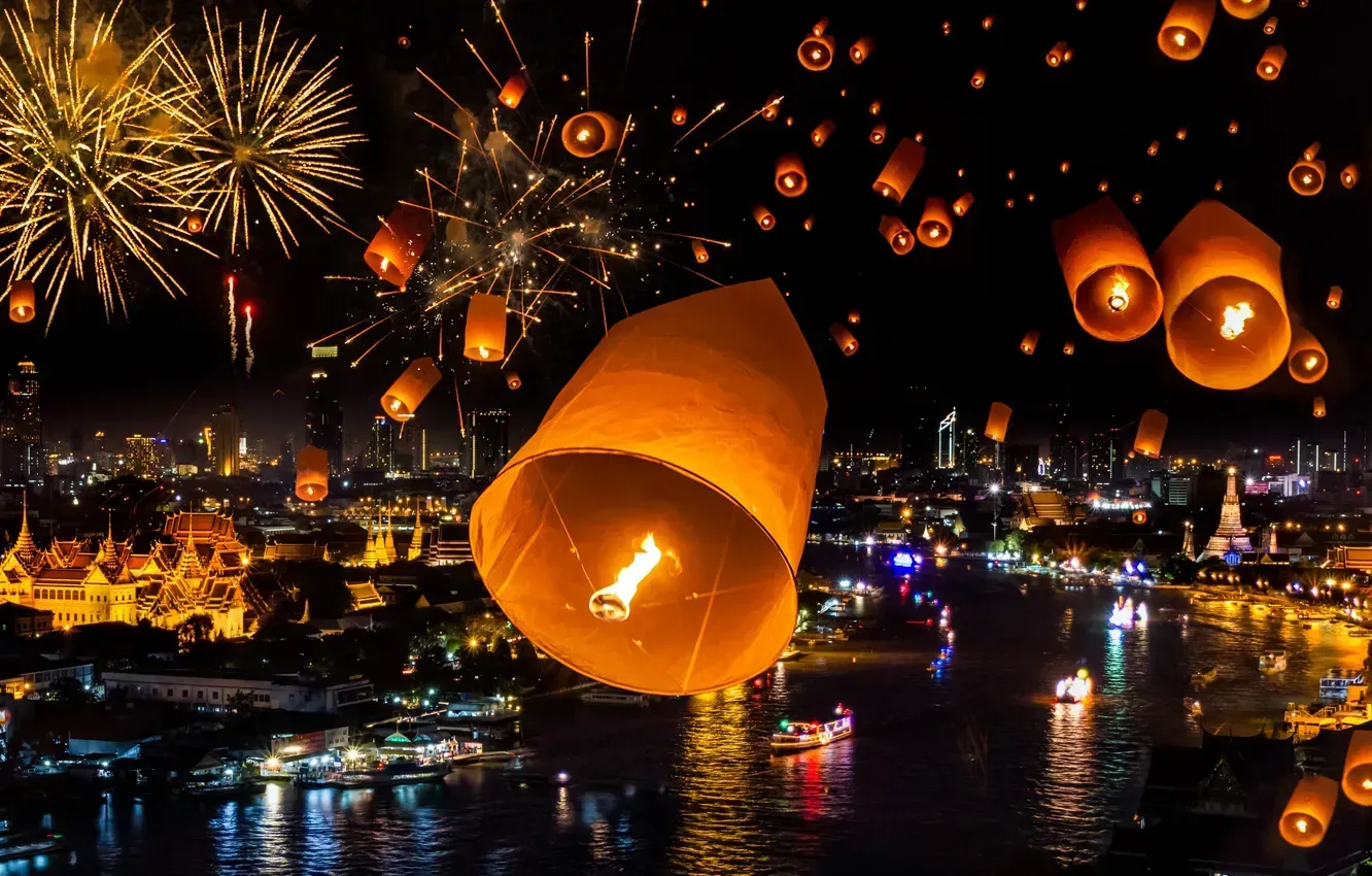 Floating lanterns illuminate a nighttime cityscape with fireworks. Bangkok Thailand
