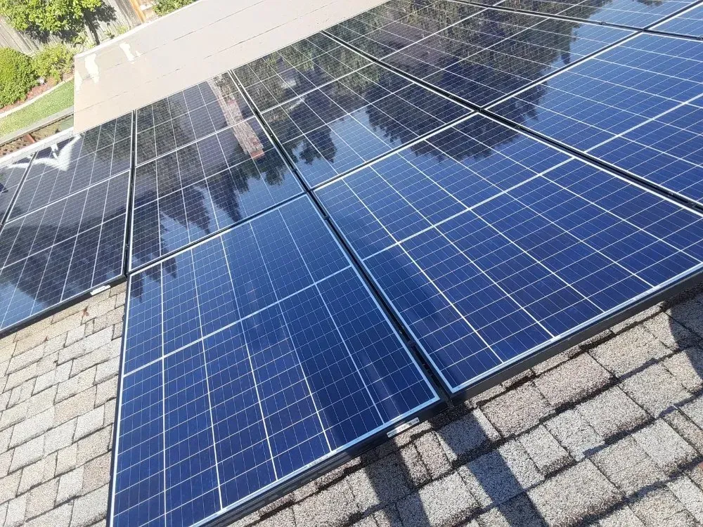 Solar panels installed on a residential roof, reflecting sunlight.