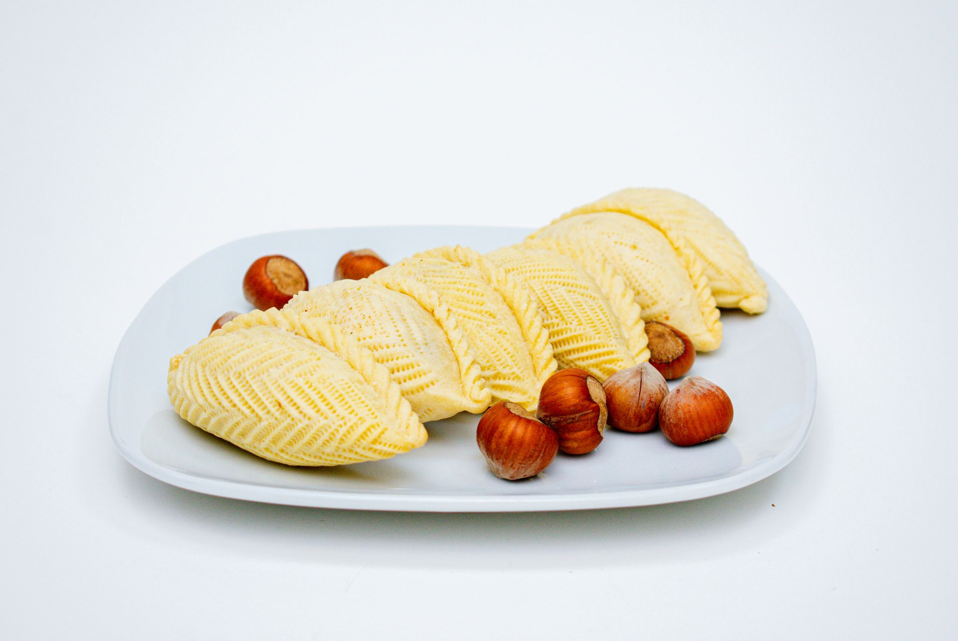 Plate of Azerbaijani pastries (shekerbura) with hazelnuts.