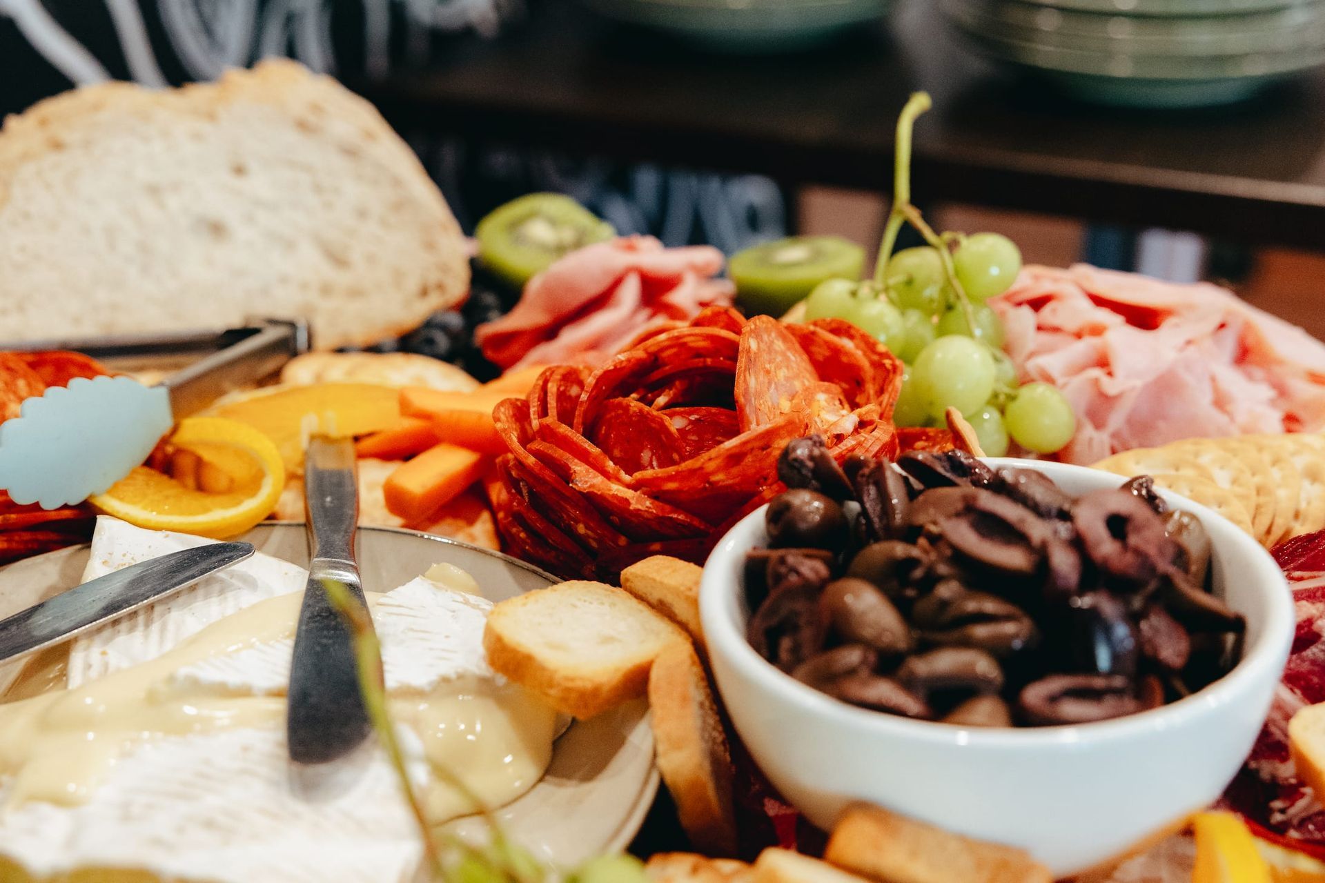 A table topped with a variety of food and a bowl of olives.