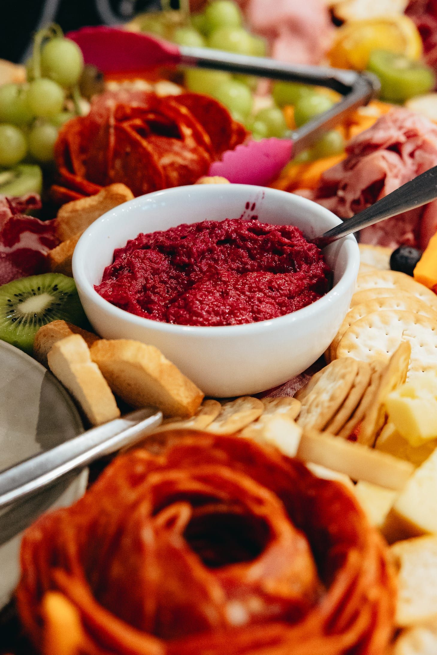A bowl of dip is sitting on top of a tray of food.