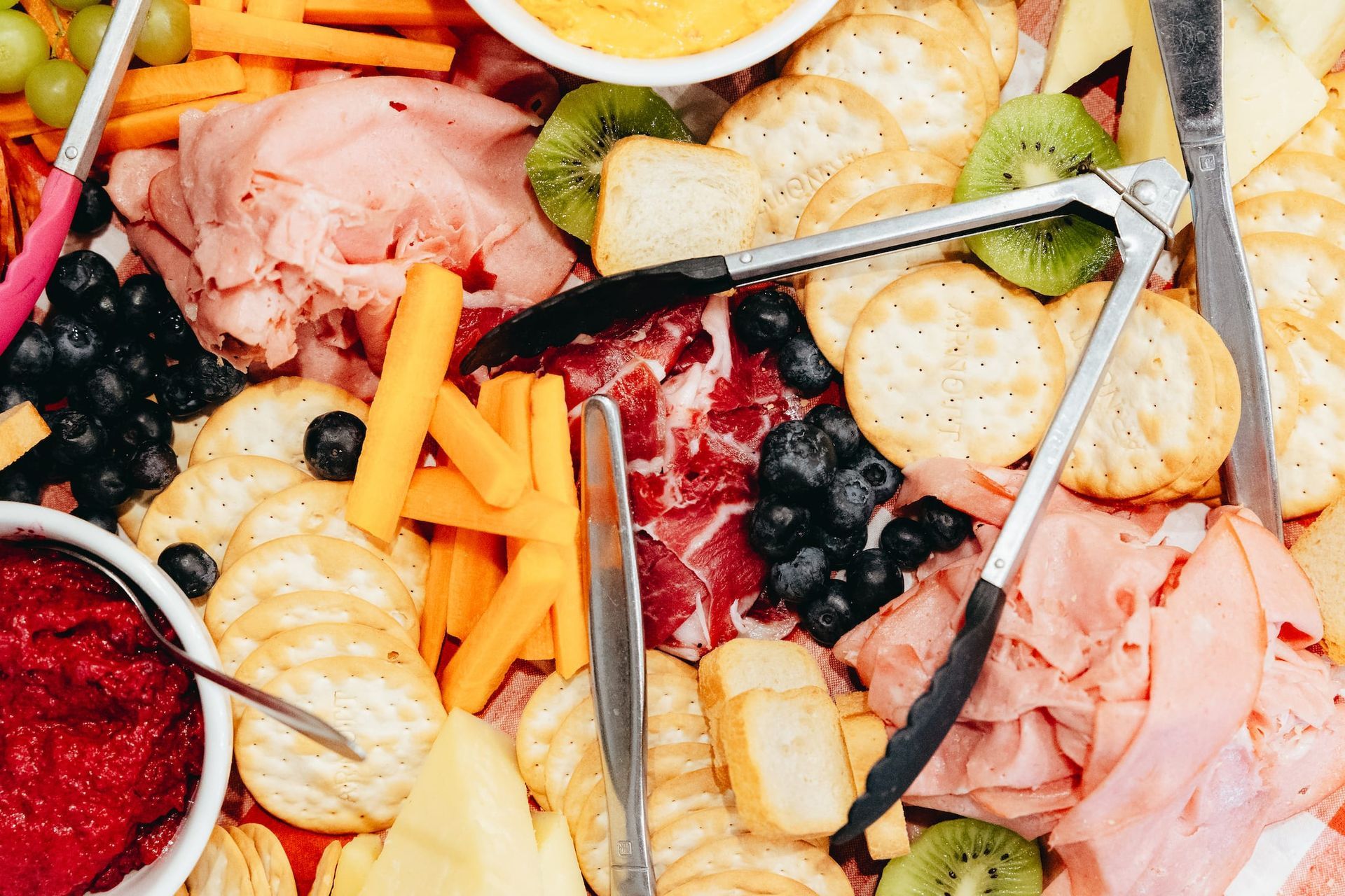 A close up of a tray of food with tongs and knives on it.