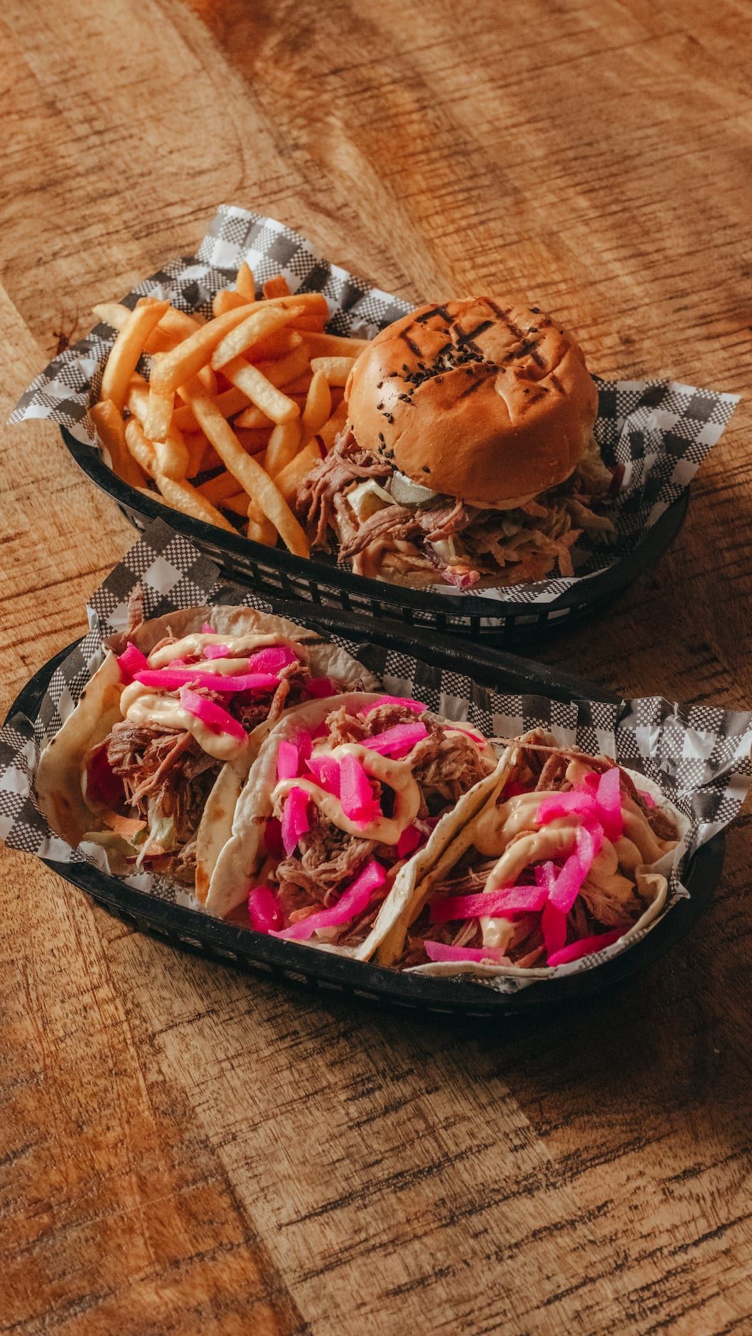 A hamburger and a taco are sitting on a wooden table.