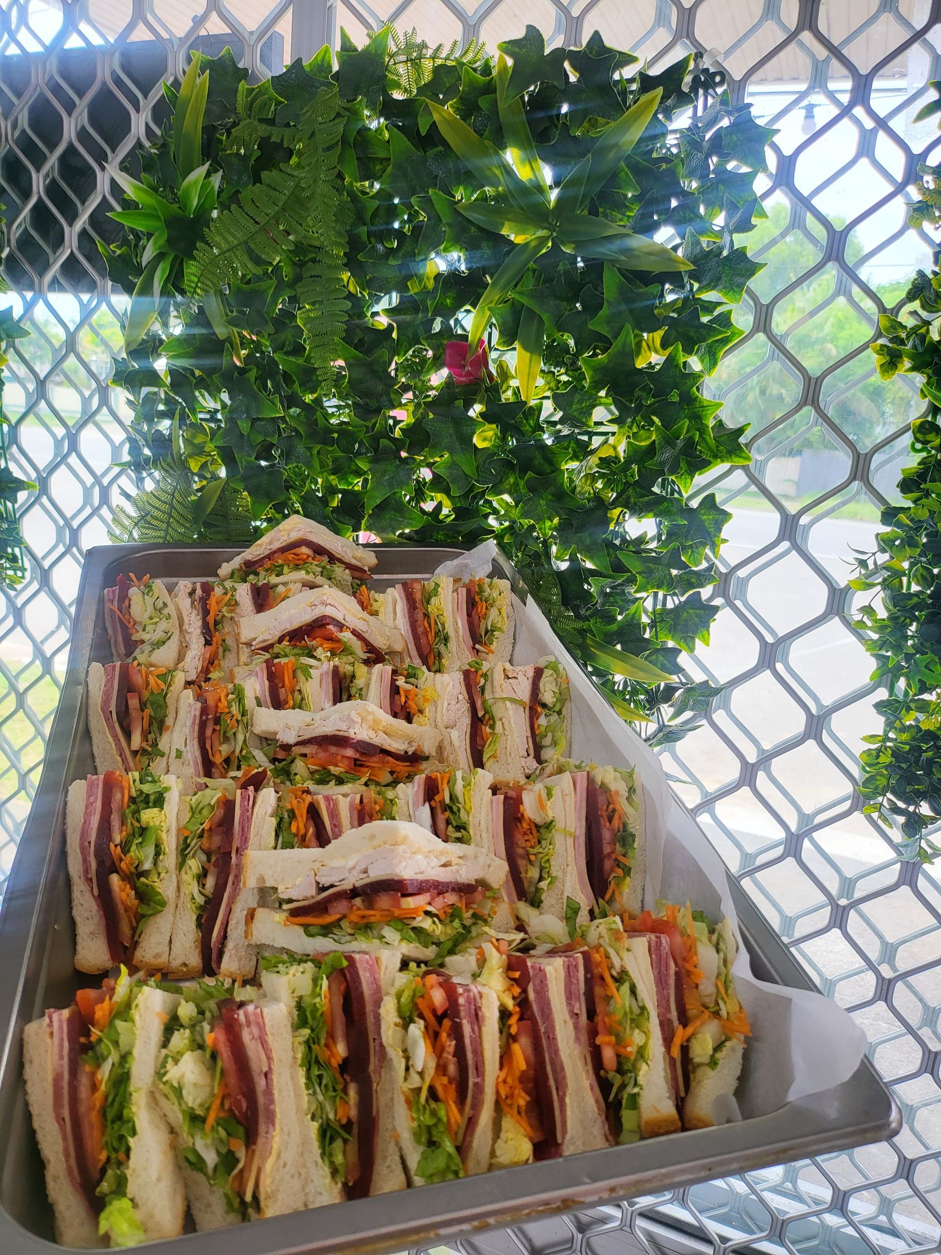 Tray of cut sandwiches, white bread, various fillings, placed in front of green leafy plants. — Boundary Street Fish & Burger Bar in Railway Estate, QLD