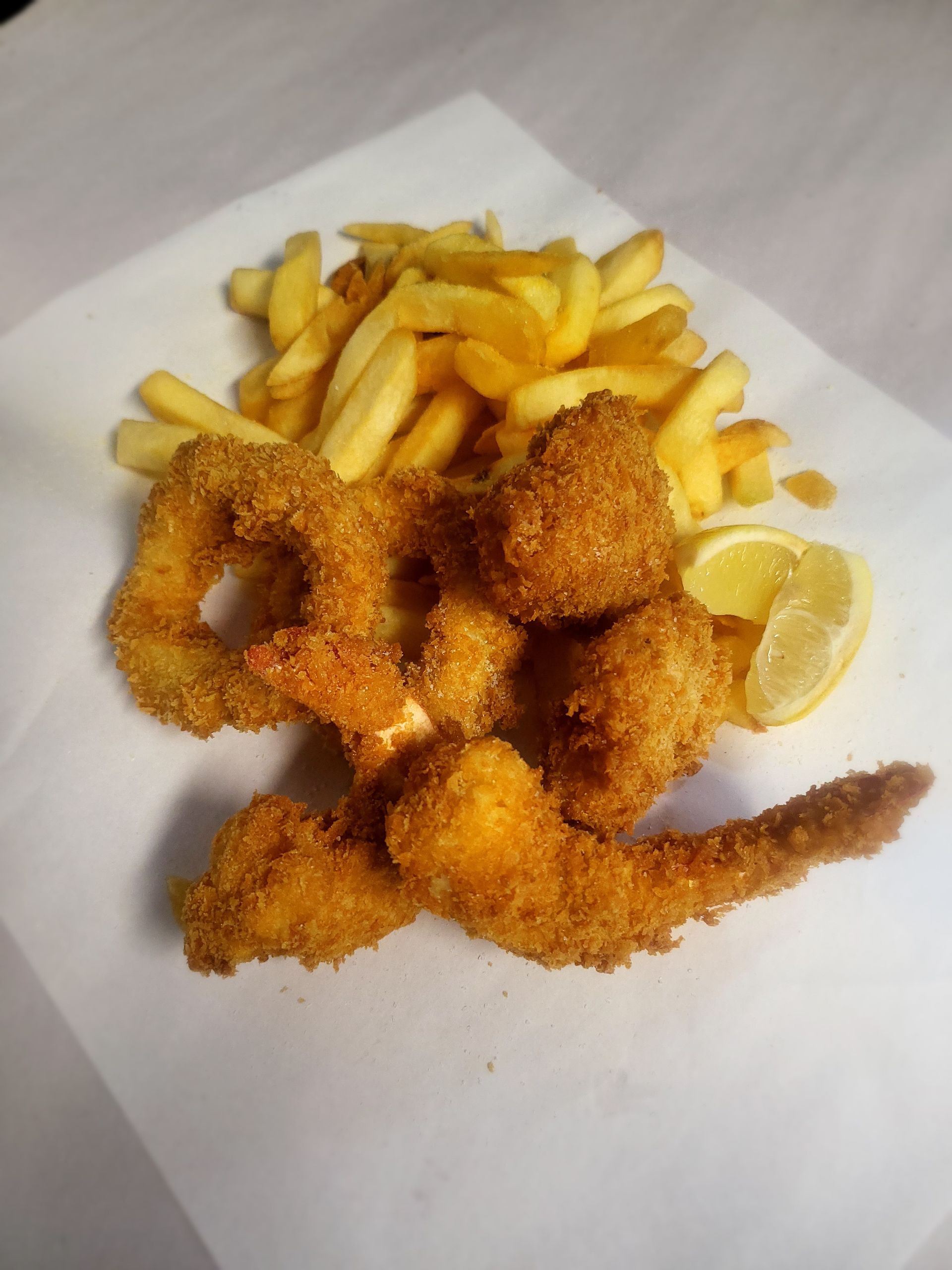 Fried shrimp and french fries with a lemon wedge on a white surface. — Boundary Street Fish & Burger Bar in Railway Estate, QLD